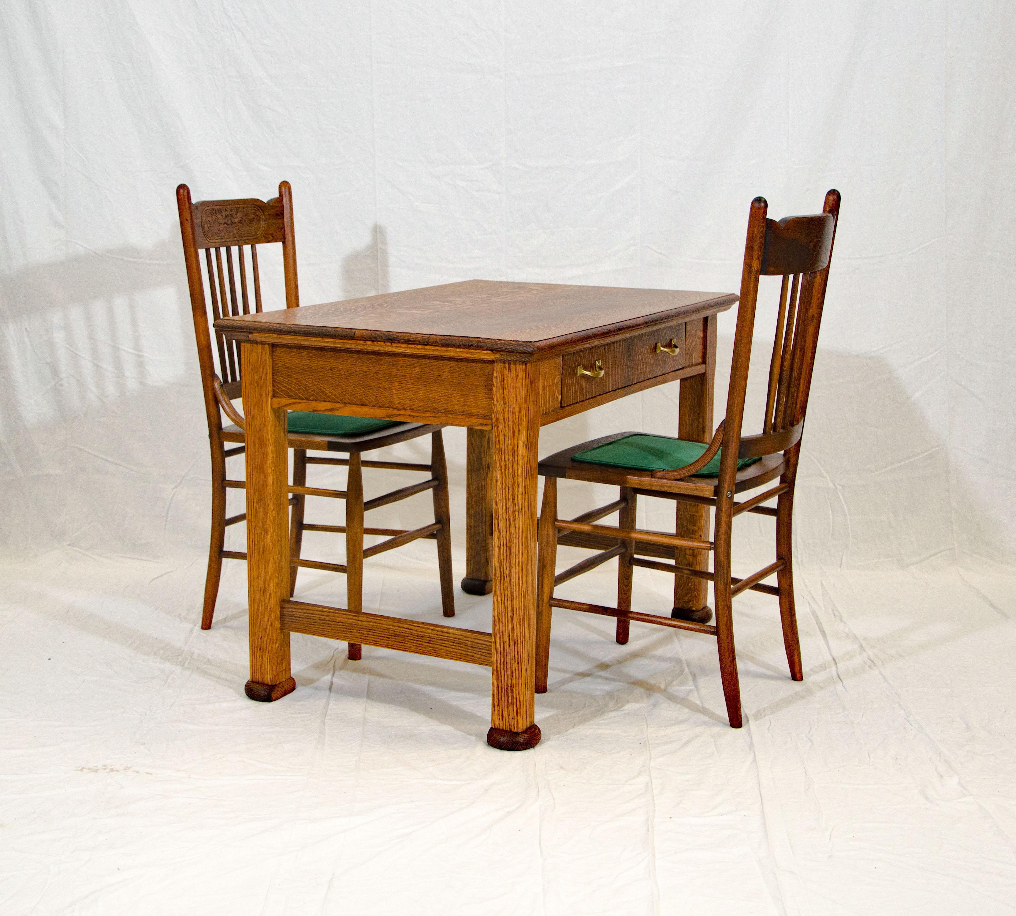 A nice quarter-sawn oak desk or library table and two pressback chairs with the face of the north wind on the back. This table could also be used as a breakfast table in a small kitchen space. The drawer interior height is 3