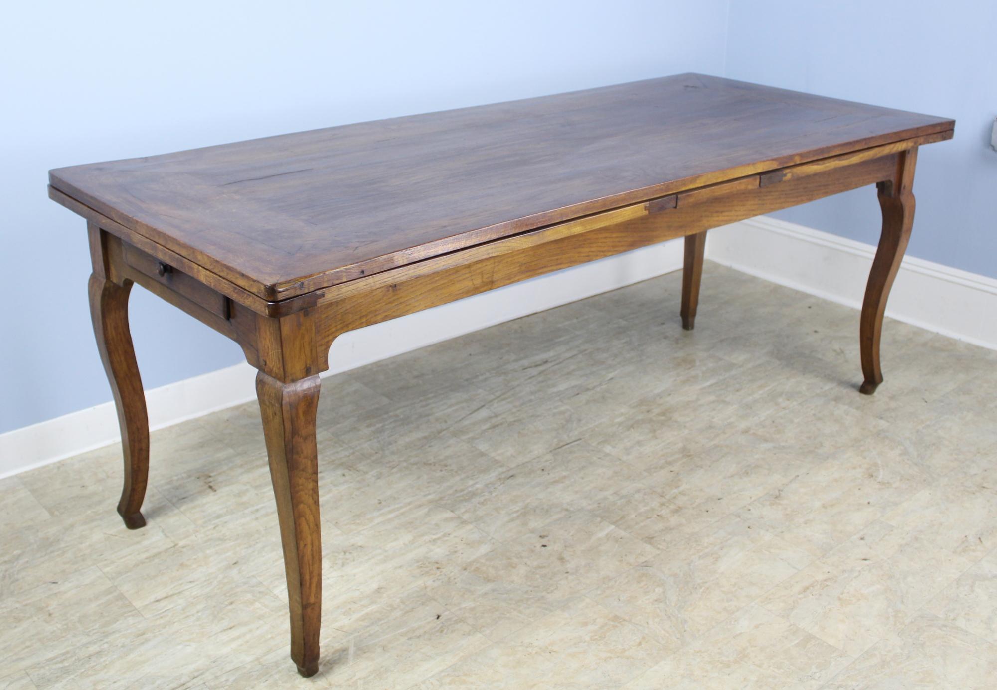A pretty oak dining or farm table from France, with classic design details -mitred corners, cabriole legs, and hoof feet - with a twist! This table extends to 145 inches -over 12 feet long, when both 34 inch draw leaves are extended. When opened,