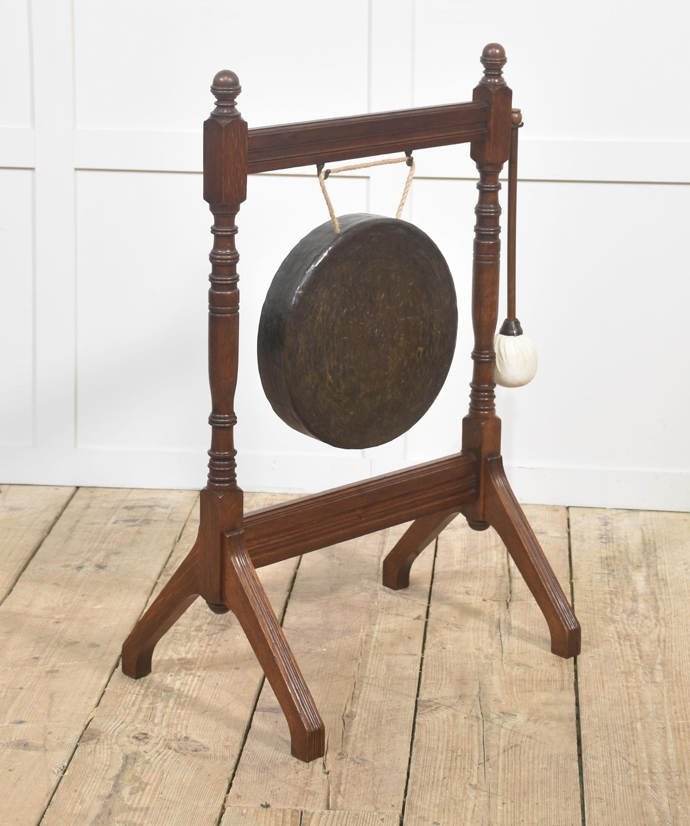 Un bel gong antico in Oak, completo del suo supporto originale in legno di quercia tornito e del percussore pad. Il gong circolare è sospeso a una corda e produce un tono ricco e risonante quando viene percosso, perfetto per l'uso tradizionale di