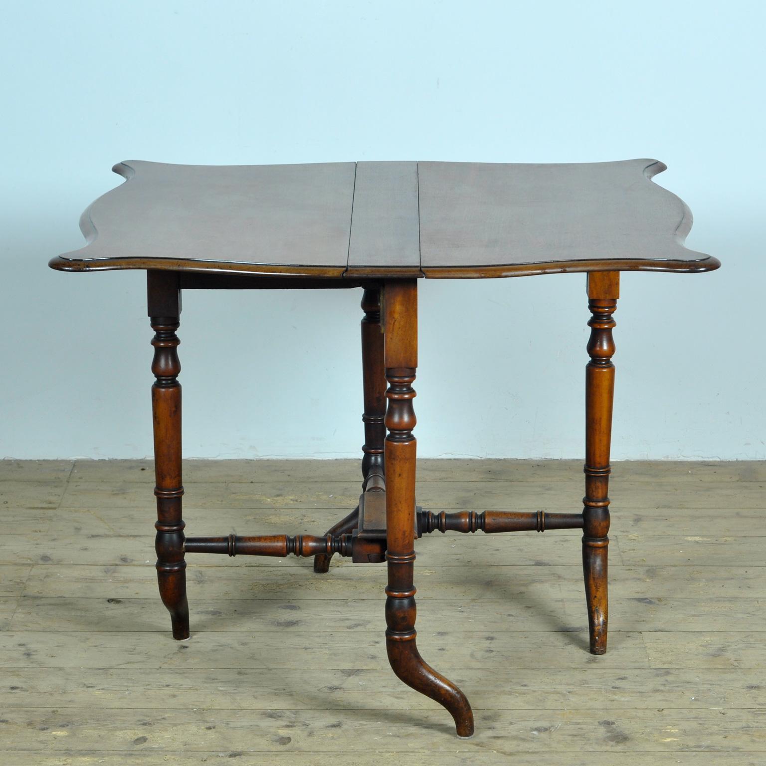 An English 19th century drop leaf table with folding top and beautiful turned legs. This English folding table, from the first half of the 19th century, has a square top with elegant round corners made of two folding leaves, sitting above a
