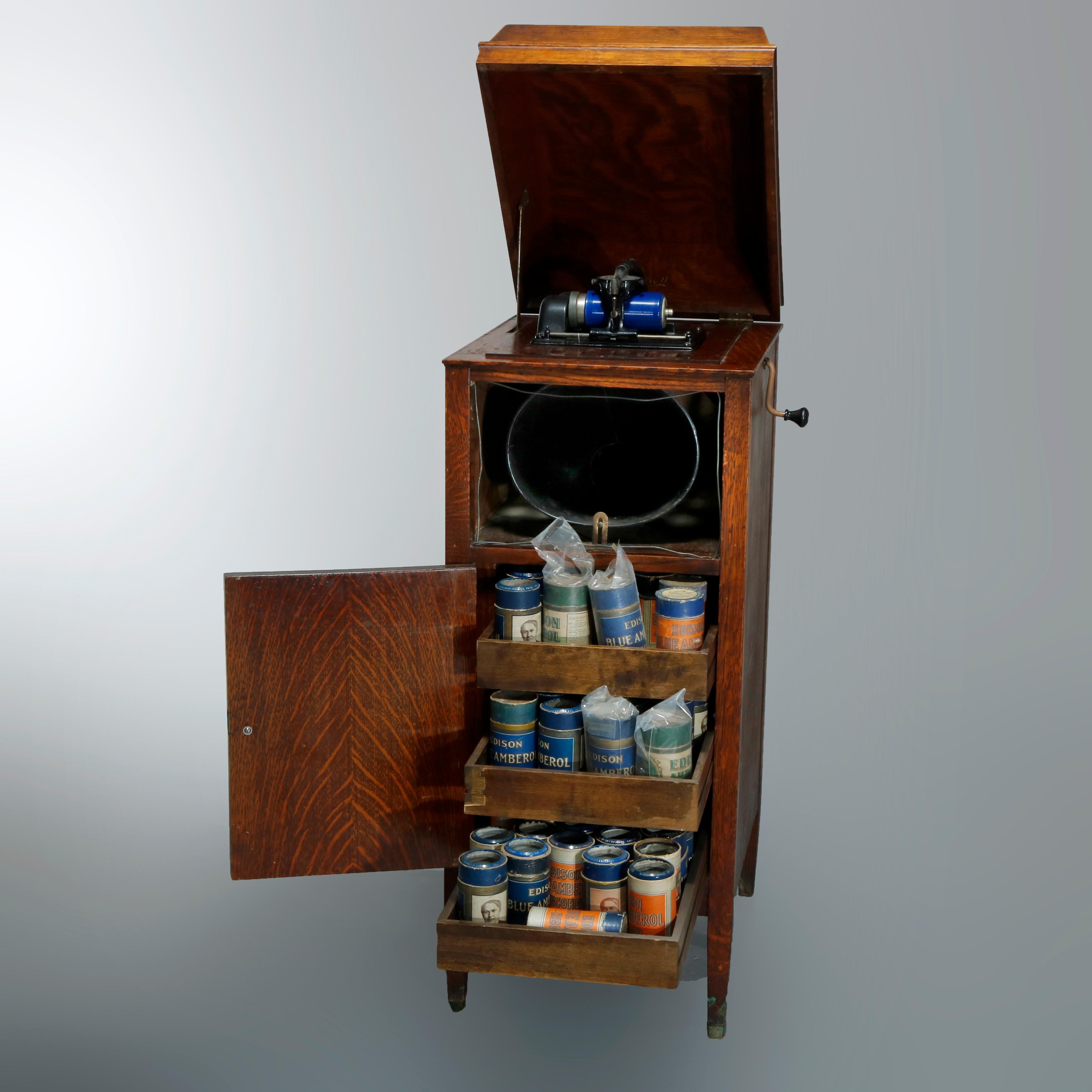 An antique Edison Floor Model cylinder phonograph offers quarter sawn oak construction with domed lid opening to player and surmounting lower single drawer cabinet having slide-out shelved interior with cylinders, raised on tapered square legs,