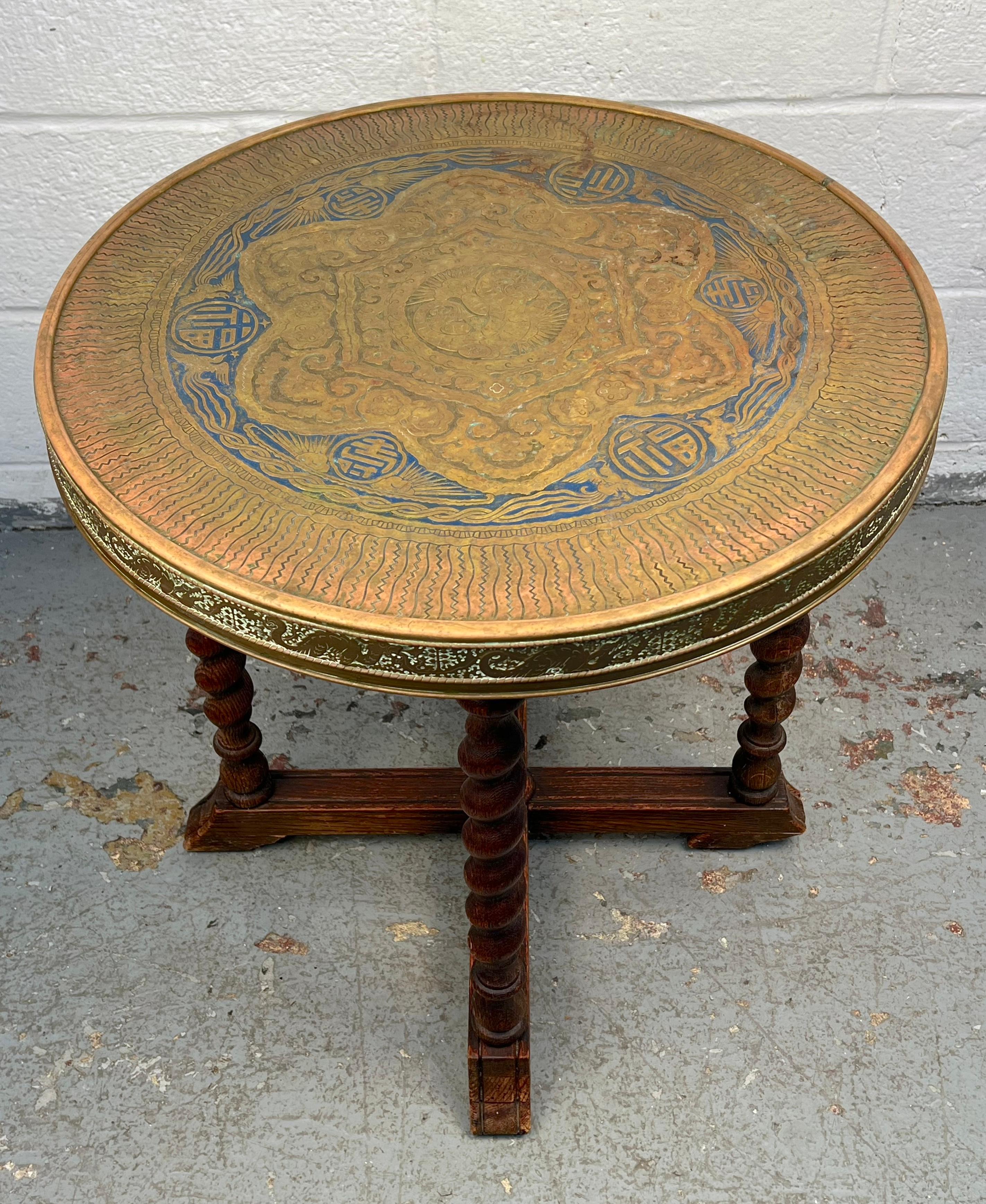 An exceptional antique brass round table by Ferguson Brothers Mfg., dating to the 1920s. The tabletop is adorned with an intricate dragon design, showcasing detailed craftsmanship and bold decorative appeal. Supported by spiral legs, the table