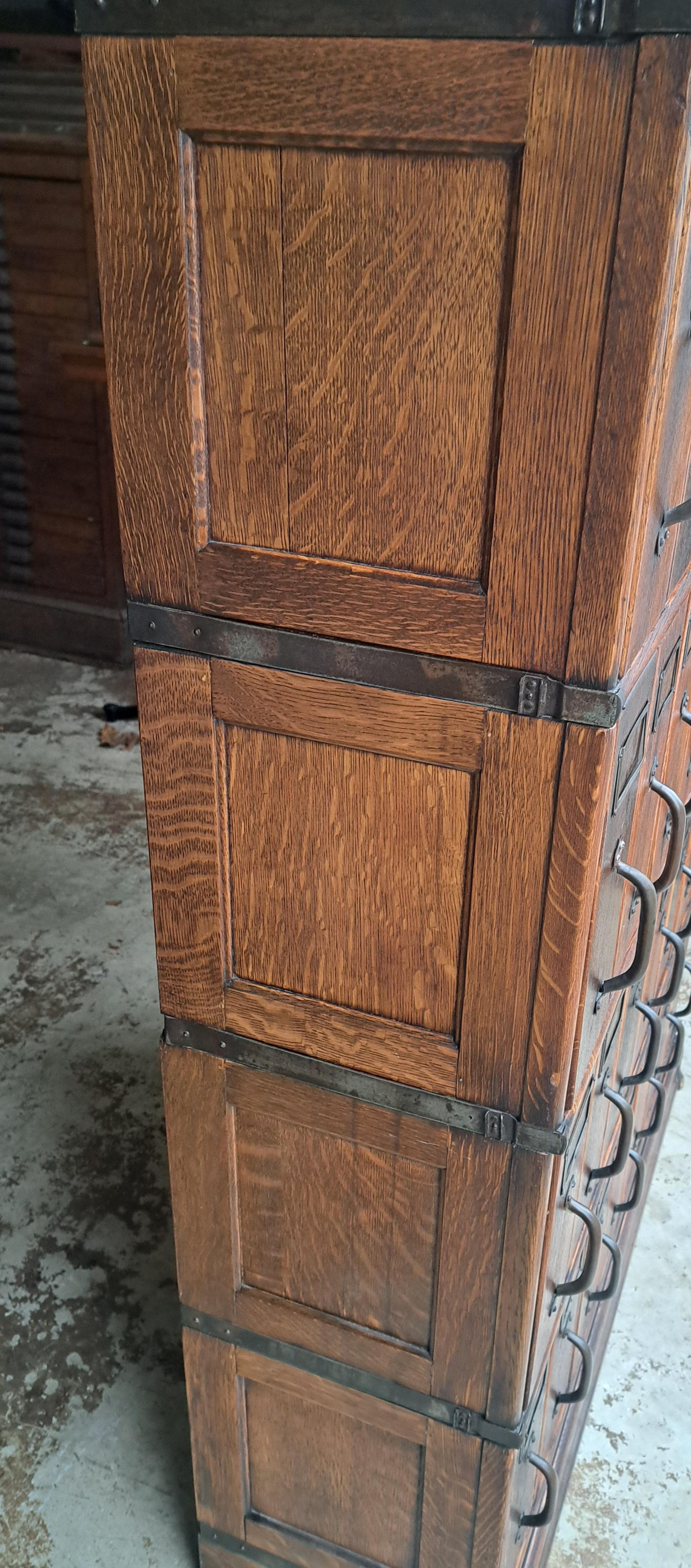 Oak 28 Drawer File Cabinet attributed to globe Wernicke.  Shows discoloration and one screw is broken on the handle at the bottom.  The back of the cabinet is distressed as shown.  It is 13.5