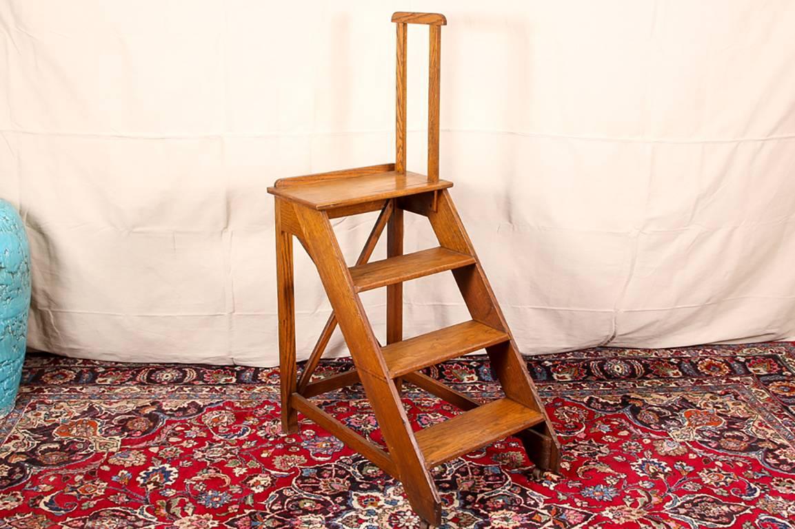 Antique  library steps, oak, four steps with a tall side support on the top step, quare back legs with an X-stretcher and three base stretchers, front feet on casters. 

Condition: Expected wear and signs of use including some light surface