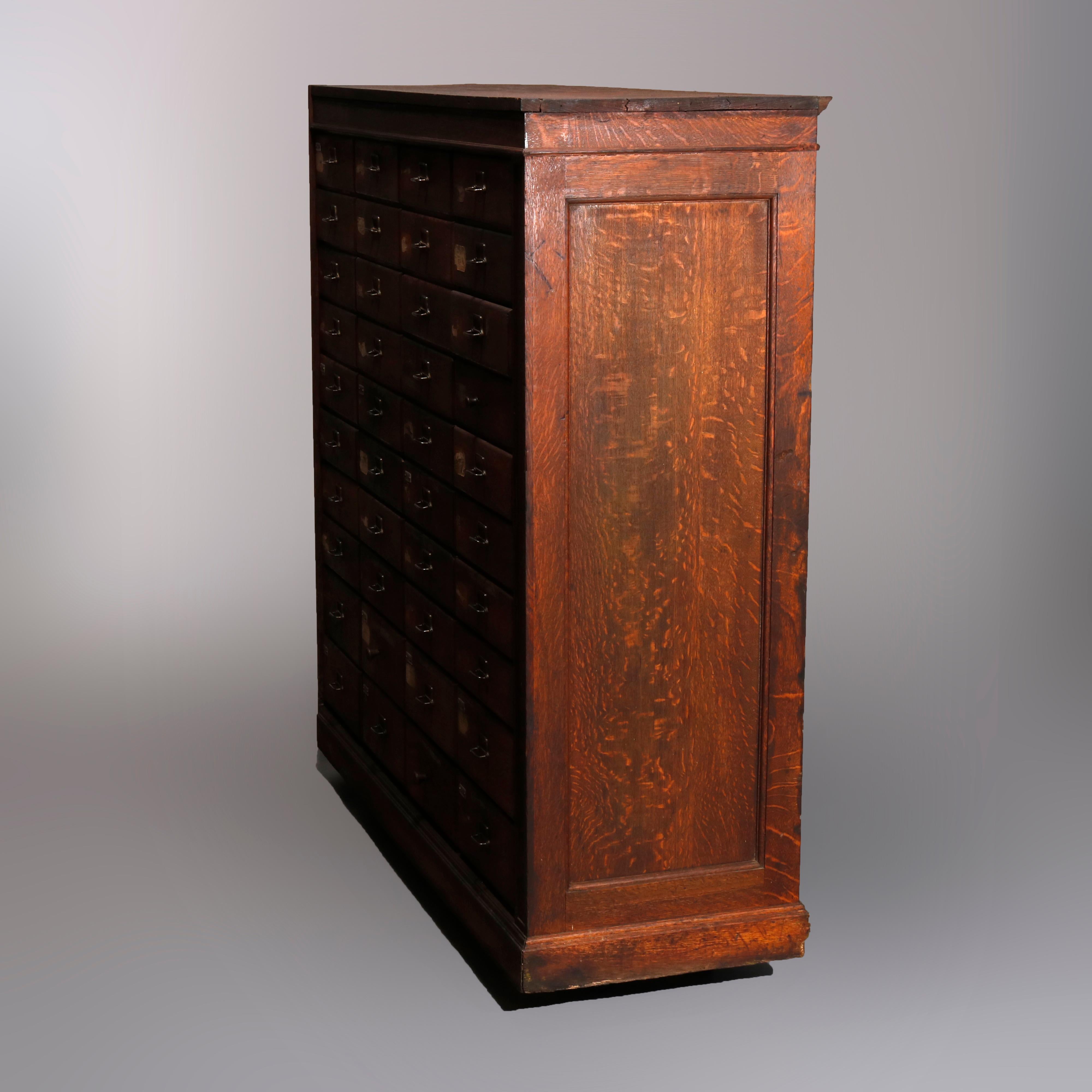 An antique card catalog 40 drawer filing cabinet offers paneled oak case with four drawer columns having ten drawers each (eight narrow drawers over two deeper drawers), c1900

Measures- 77.5
