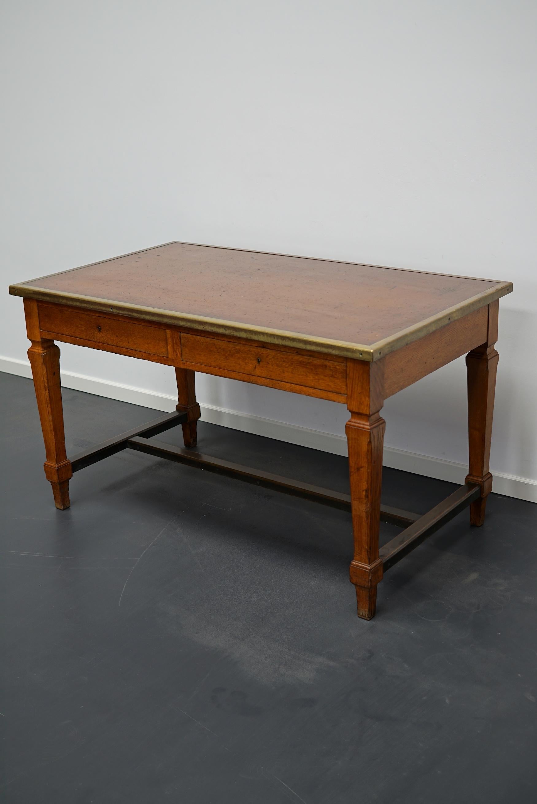 This art deco style desk or writing table was made around the 1920s in France. It is made from oak with a linoleum top and brass edging. It was used in Banque de France in the city Rouen. The floor to apron height is 60 cm.