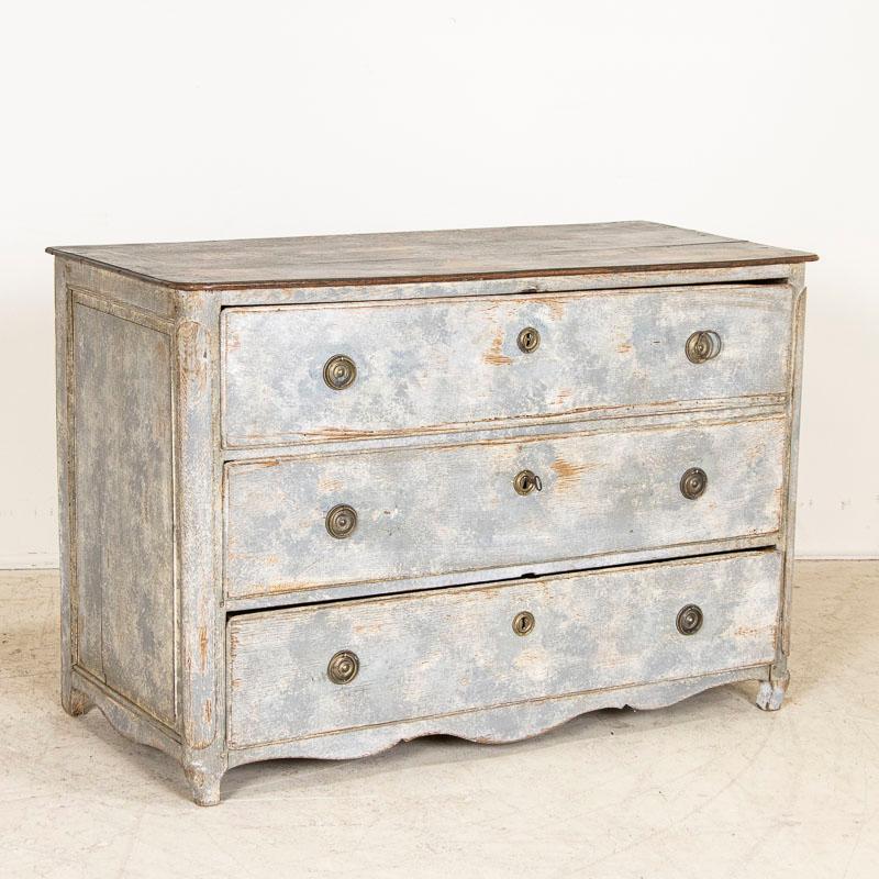 The painted finish is captivating in this large chest of three drawers from France. The newer gray paint reveals layers of blue and eggshell adding a touch of grace while the gentle distressing reveals the natural oak beneath. The contrasting black