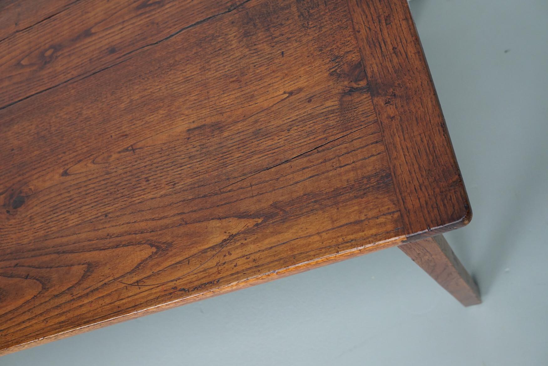 Cette élégante table a été fabriquée en France au début du 20e siècle. La table a été fabriquée en chêne massif avec de magnifiques veinures. La couleur est très chaude et la table présente des marques d'utilisation, des réparations anciennes et une