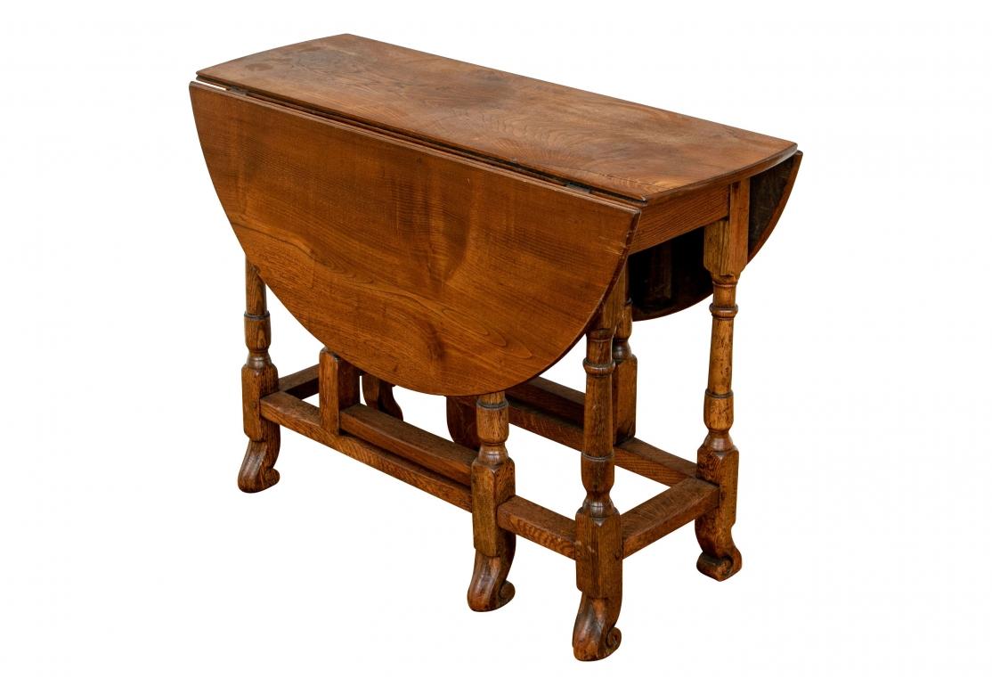 A handsome and very well made Antique Tavern Table with unusual and very decorative form. A round drop leaf table with interesting heavy carved block stretchers with turned gate legs. Ending in scrolled paw feet. 
Lovely rich tone to the oak and a