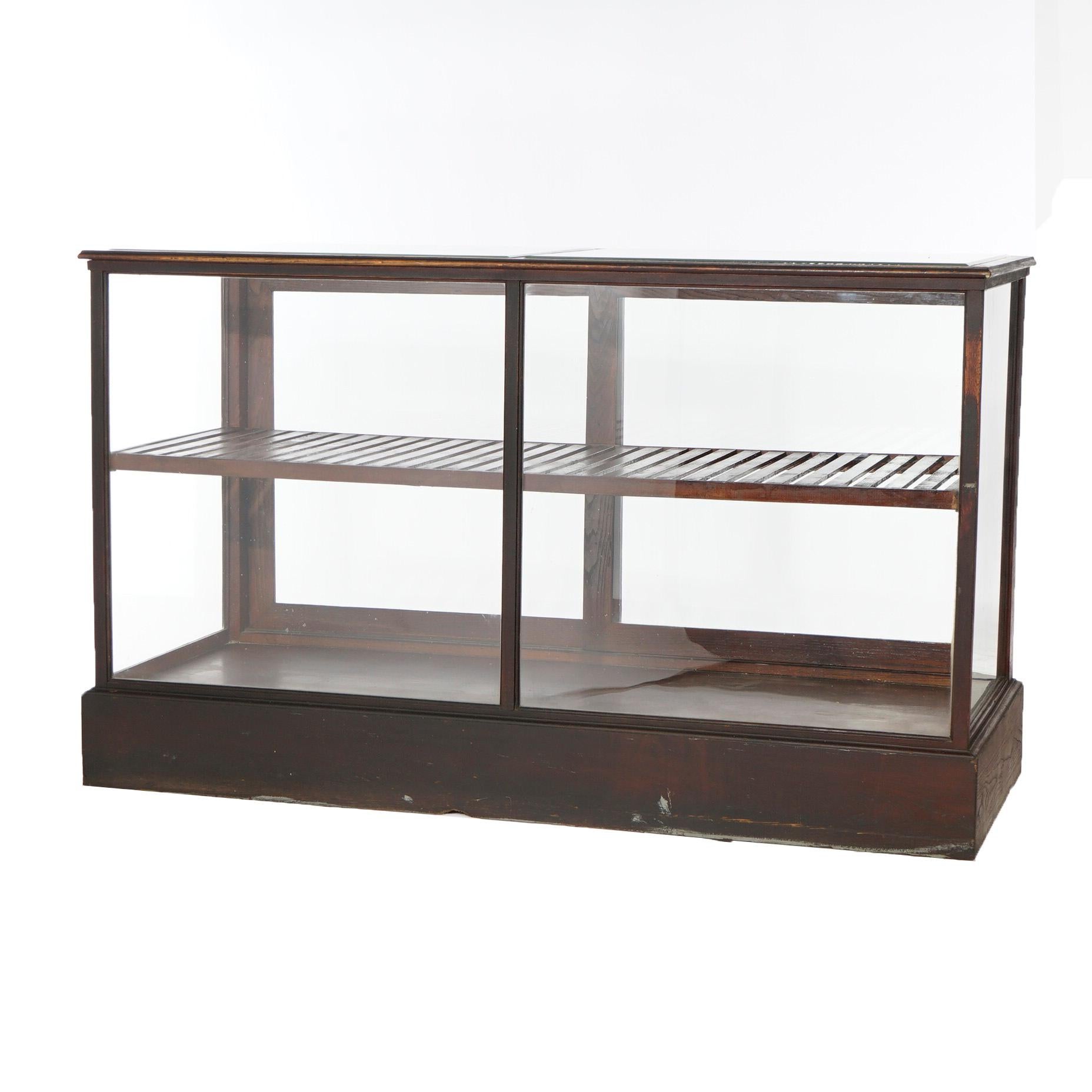 An antique country store display case offers oak construction with case at counter height and sliding glass doors opening to slat shelf interior, c1900

Measures- 43.25'' H x 72'' W x 29'' D.