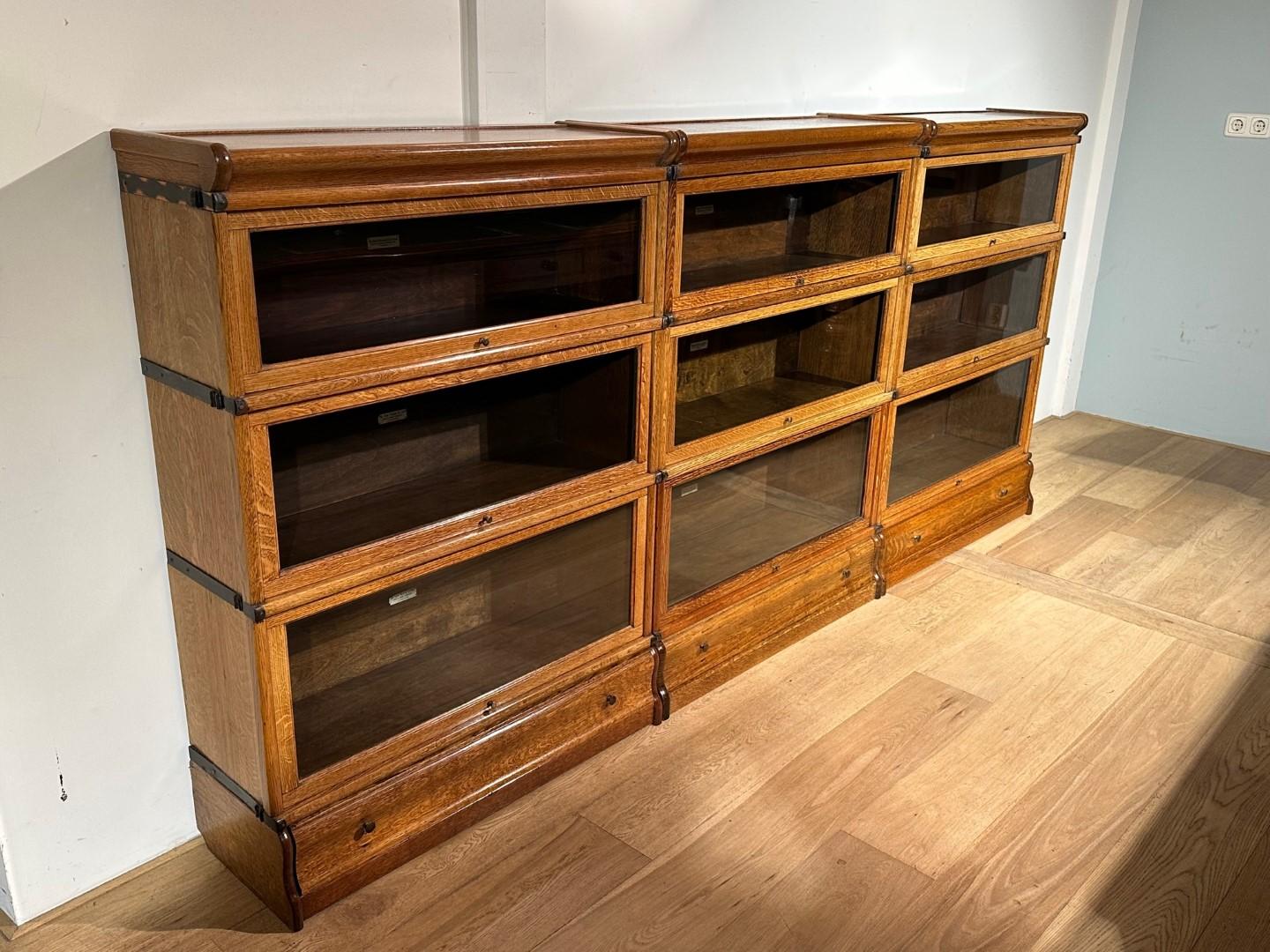 Beautiful antique oak Globe Wernicke bookcase in perfect condition. Cabinet consists of 9 stackable parts with 3 feet with drawers and 3 hoods. Beautiful warm light oak color.
Origin: England
Period: Approx. 1895-1910
Size: Br. 260cm x 29cm x