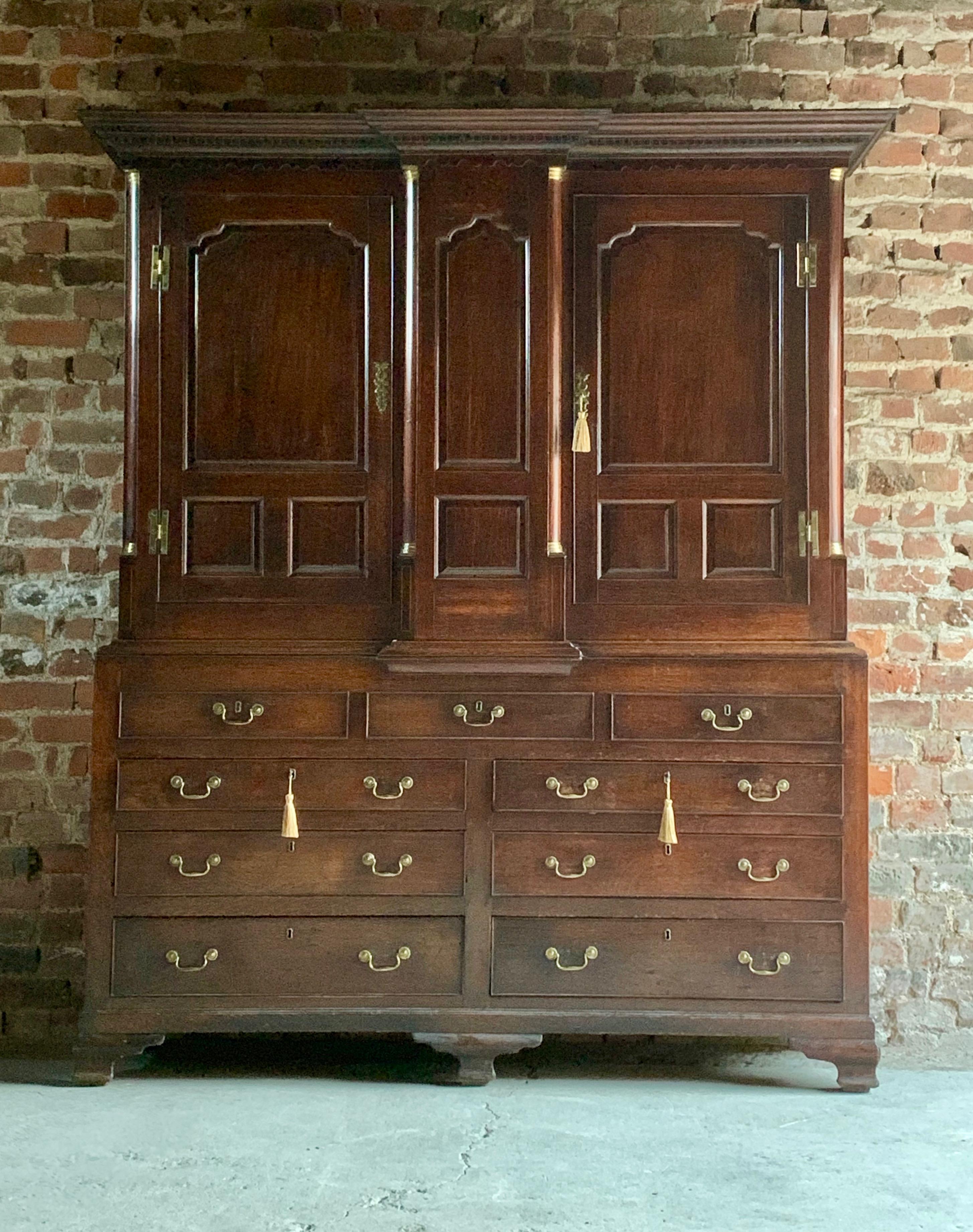 18th century George III oak housekeeper's cupboard, circa 1790, the upper breakfront section with dentil moulded cornice above two fielded panelled doors flanked by brass capped rounded quarter columns to a base of three dummy drawers above two