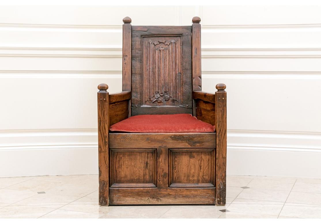 A handsome English Antique Chair in the Jacobean style with handsome grained Oak, paneled front and sides, generous flaring seat and Ribbon and Foliate carving to the back. Very solid feeling with good weight and a Salmon Velvet seat cushion.