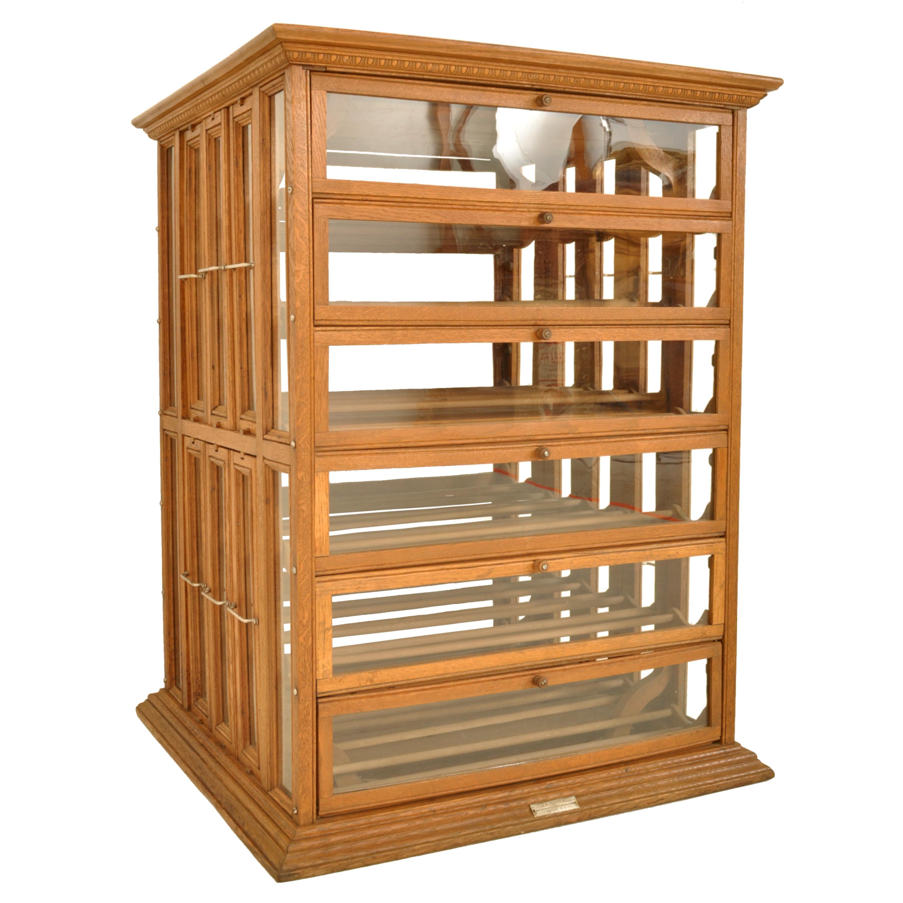 Antique oak mecantile store ribbon spool cabinet, wine or liquor cabinet, A.N. Russell Ilion, NY, circa 1900.
The cabinet having a dentil molded frieze to the top, the cabinet having six pull down doors to the front and back with a storage area