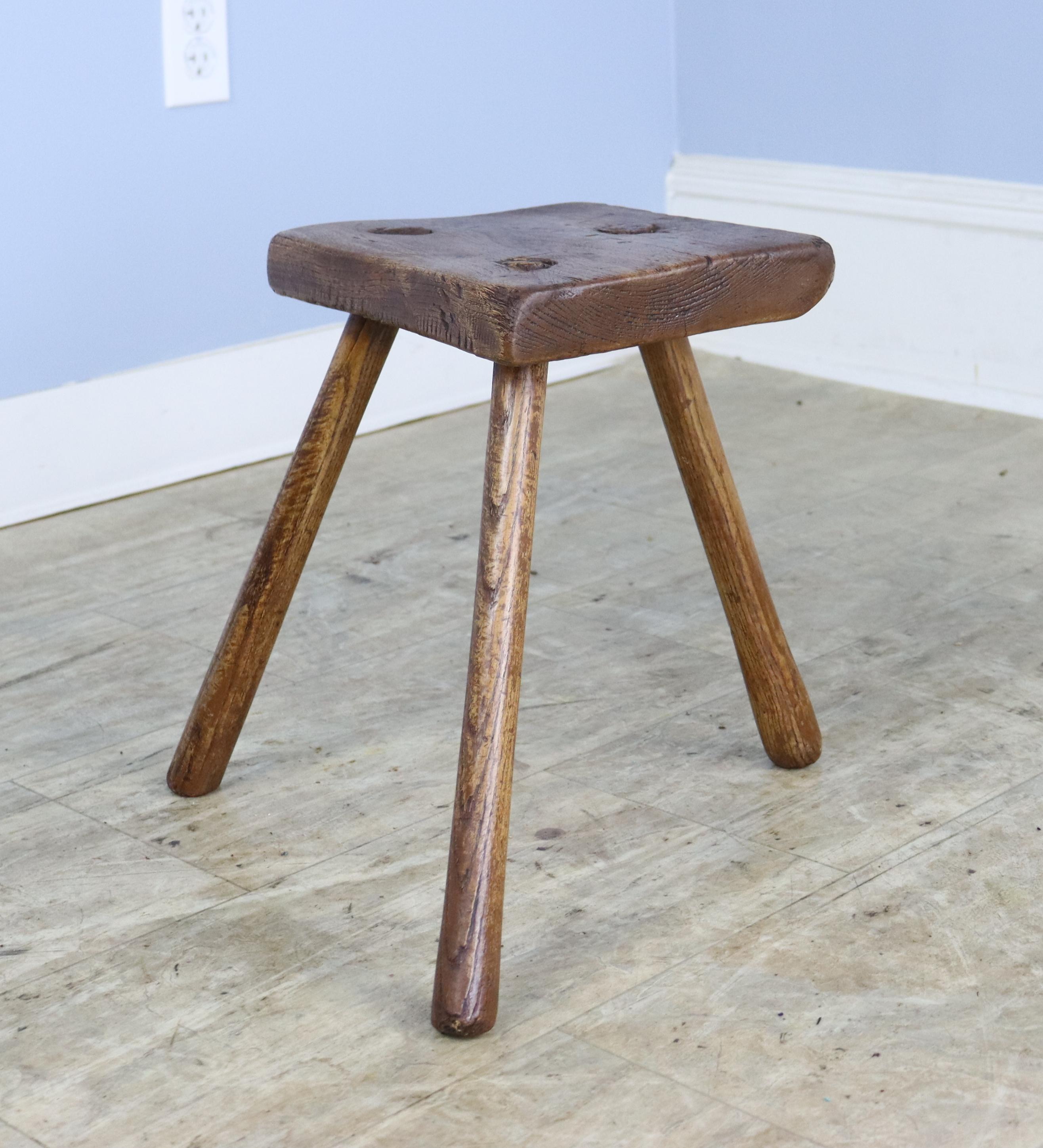 A small English country oak milking stool.  Three legged for stability when milking!  Charming as a fireside child's seat or a perch for your drink. 