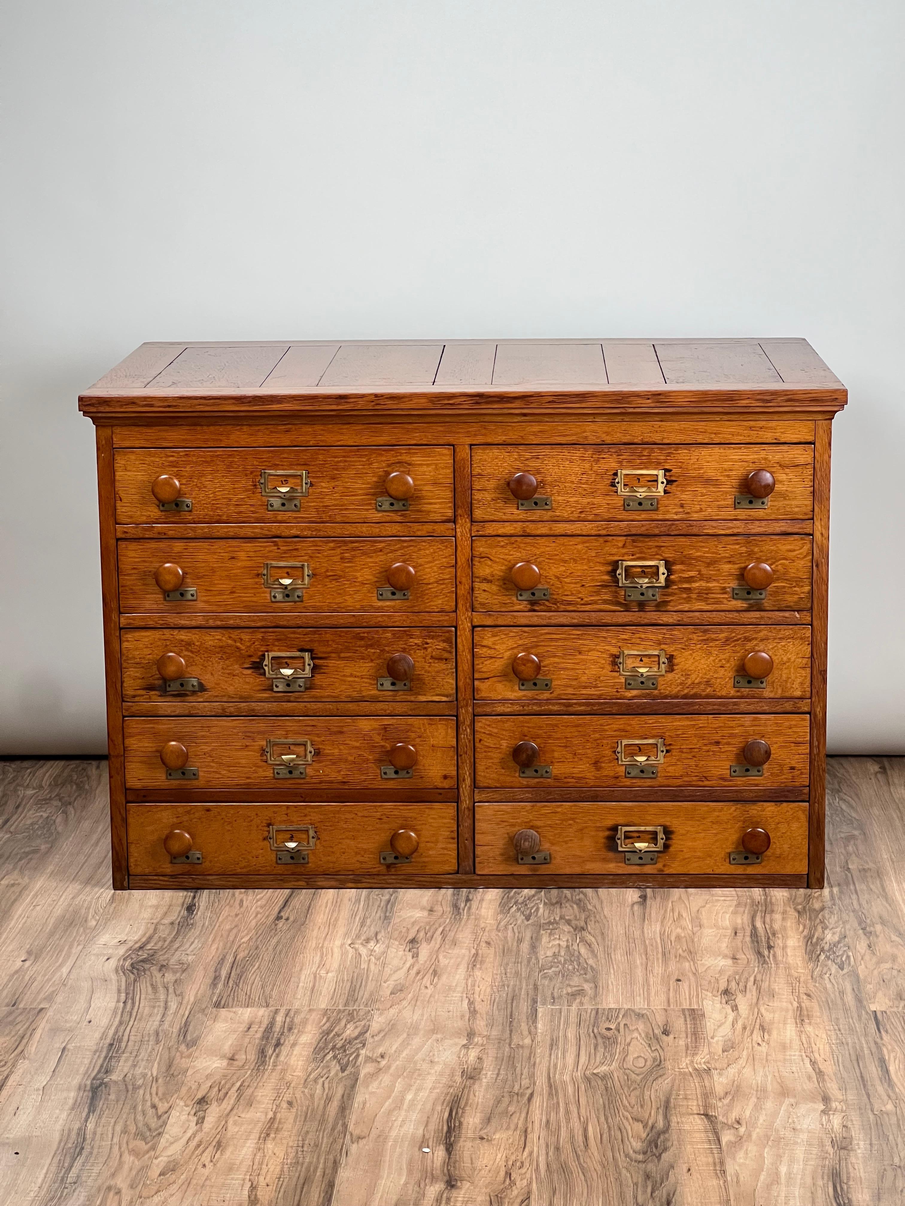 Un bellissimo schedario antico a 10 cassetti in Oak risalente all'inizio del XX secolo, che offre un'archiviazione pratica e un carattere senza tempo. Realizzato in rovere massiccio, l'armadio dispone di dieci cassetti con originali portacarte in