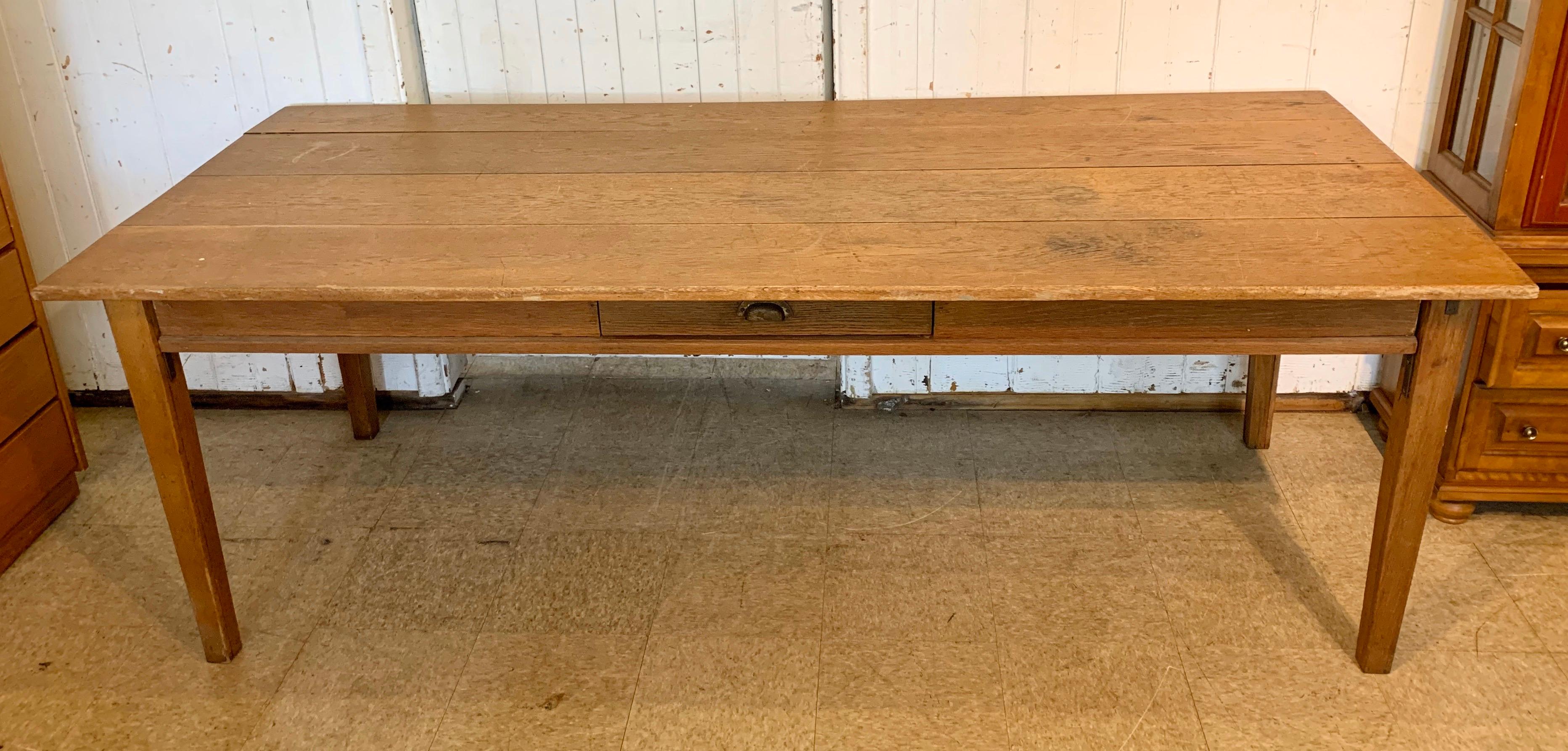 An antique 19th century farmhouse table with a rich and beautiful patina; with a single drawer on one side and two drawers on other side. Four plank top, and tapering legs.