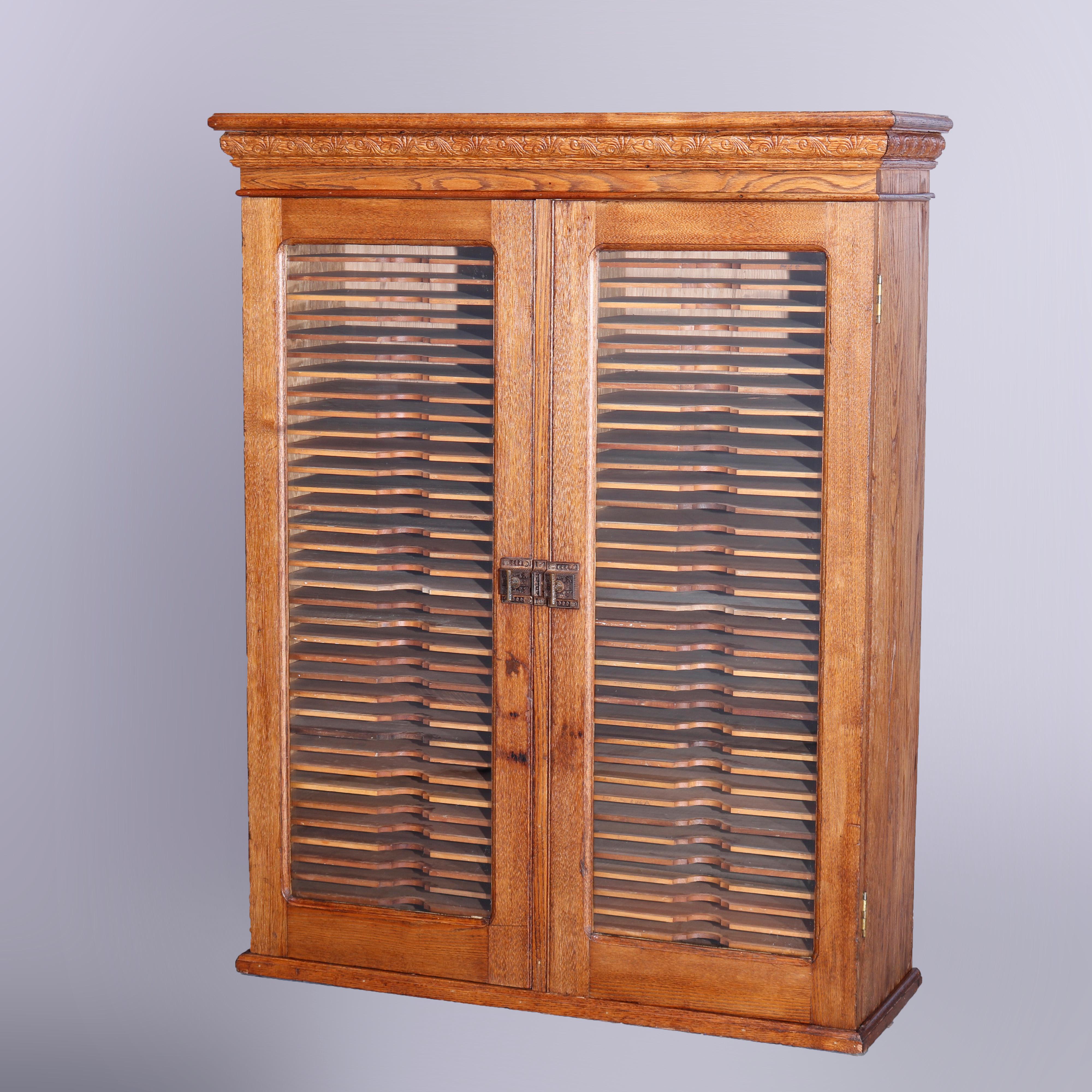 An antique hanging postmaster wall cabinet filer offers oak construction with double glass doors having stylized foliate cast latch and opening to shelved interior, c1900

Measures - 45.5''H x 36''W x 12.5''D.