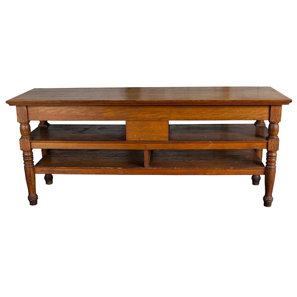 This early 20th century retail display counter has shelving and drawers for plentiful storage, making it an ideal candidate for a kitchen island. Made of solid quarter sawn oak, the chunky turned legs add a touch of easy charm to a handsome and