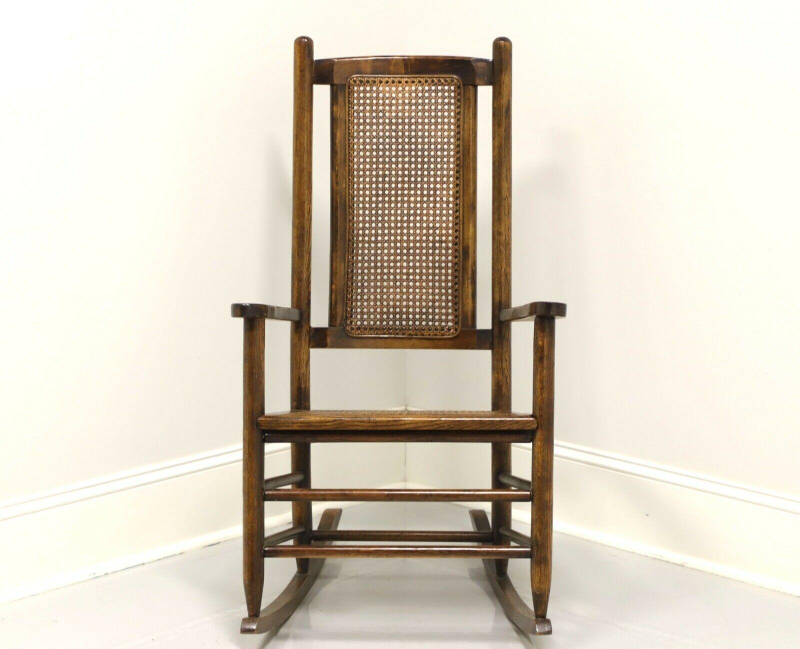 An antique American style rocking chair, unbranded. Solid oak with high back, flat arms and stretchers. Features a cane backrest and cane seat. Made in the USA, in the late 19th century. 

Measures: Overall: 23 W 29.75 D 41 H, Seat: 18.5 W 16.5 D