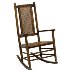 Fauteuil à bascule ancien en chêne avec assise et dossier cannés