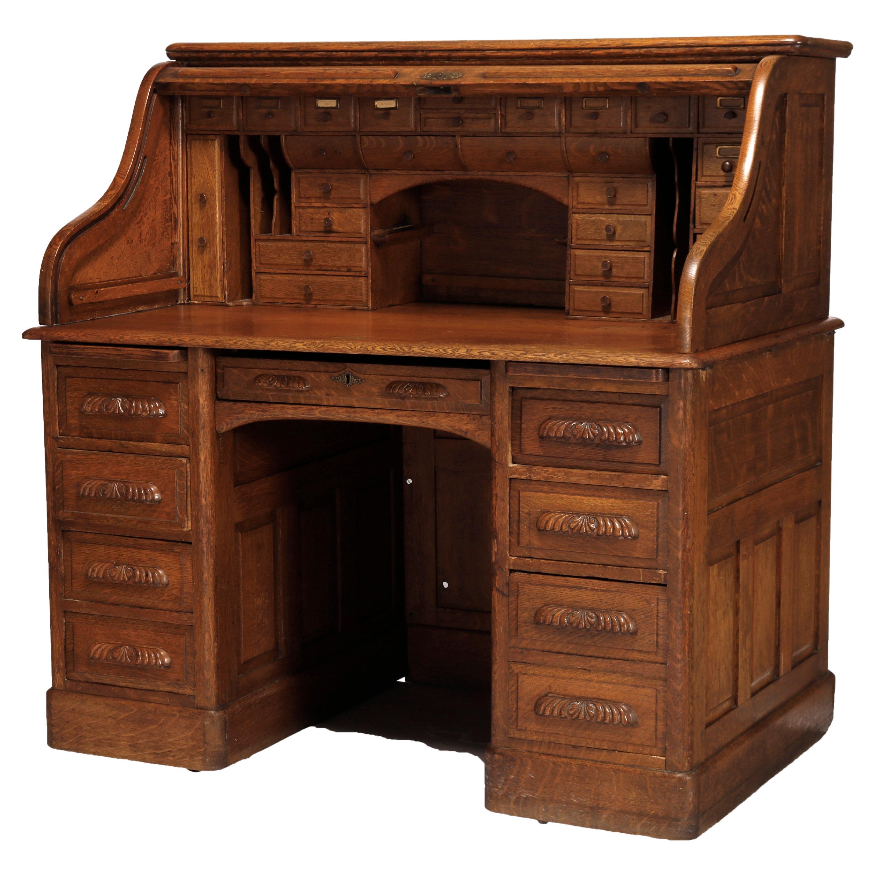 An antique desk offers paneled oak construction with s-roll top opening to full interior surmounting lower with central frieze drawer and flanking drawer towers having foliate carved pulls, c1900

Measures- 50.5''H x 49.75''W x 32''D.