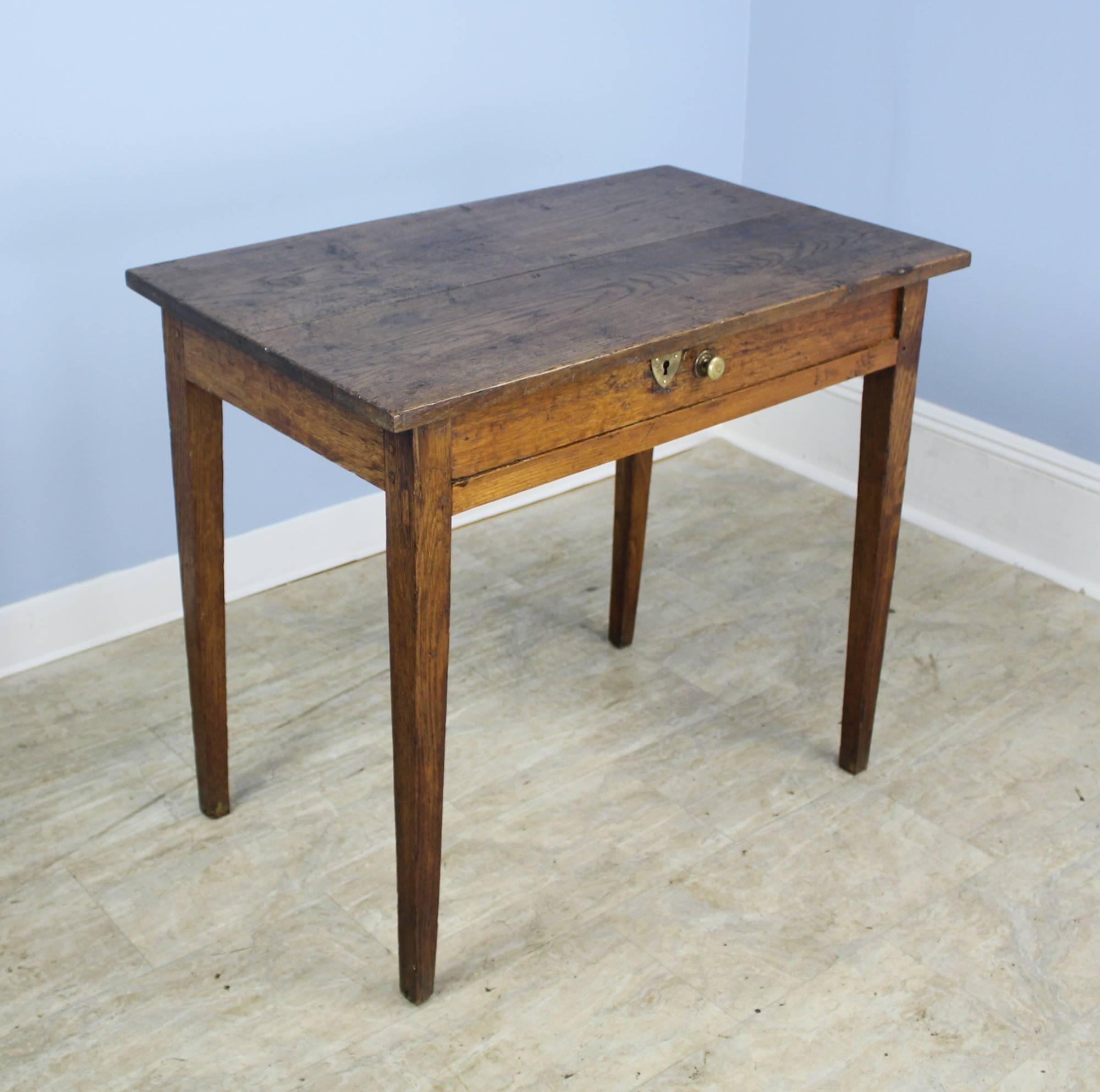 A handsome oak side table with a classic sturdy silhouette and well grained top. The wide single drawer with brass knob adds a note of drama, as does the brass keyhole.