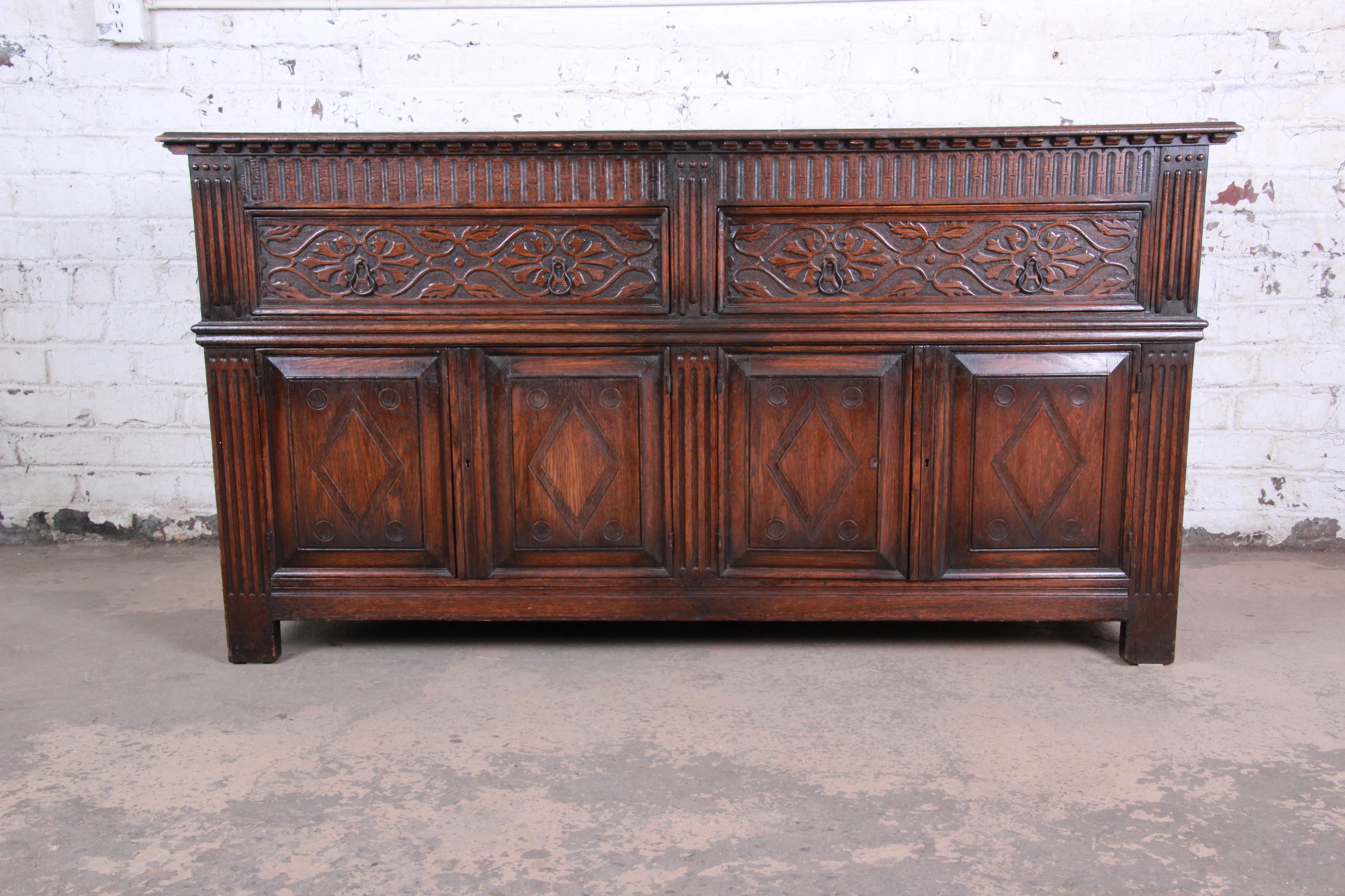 An exceptional antique carved oak sideboard or bar cabinet by Kensington Furniture Co. of New York, circa 1920s. The sideboard features solid oak construction with beautiful carved wood details. It offers ample storage. There are two deep dovetailed