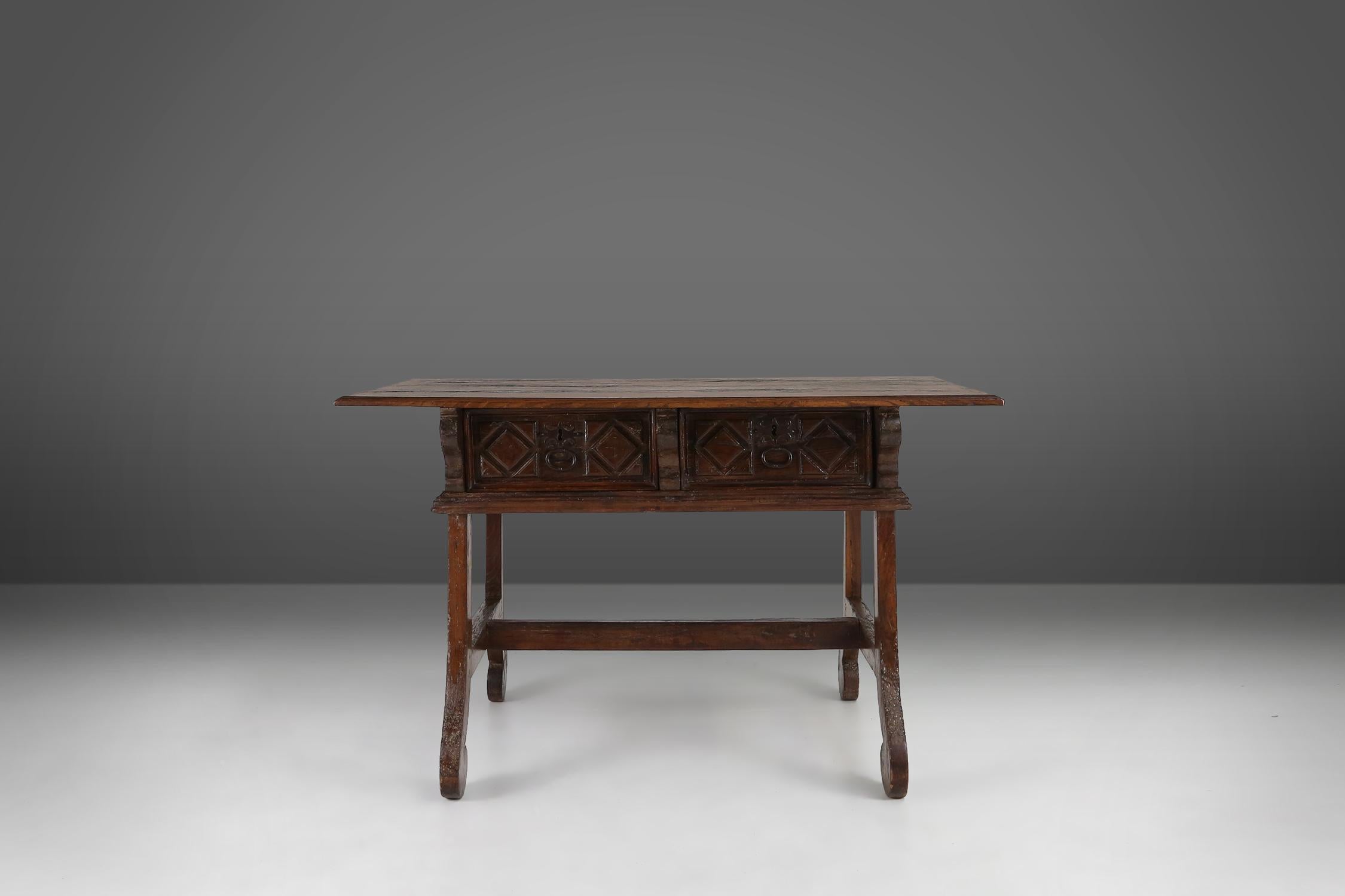 A timeless Spanish antique console table in warm oak wood with two drawers from the 18th century. 
This exquisite hand carved antique oak console table is a perfectly example of the intricate detailing and superior quality that is characteristic of