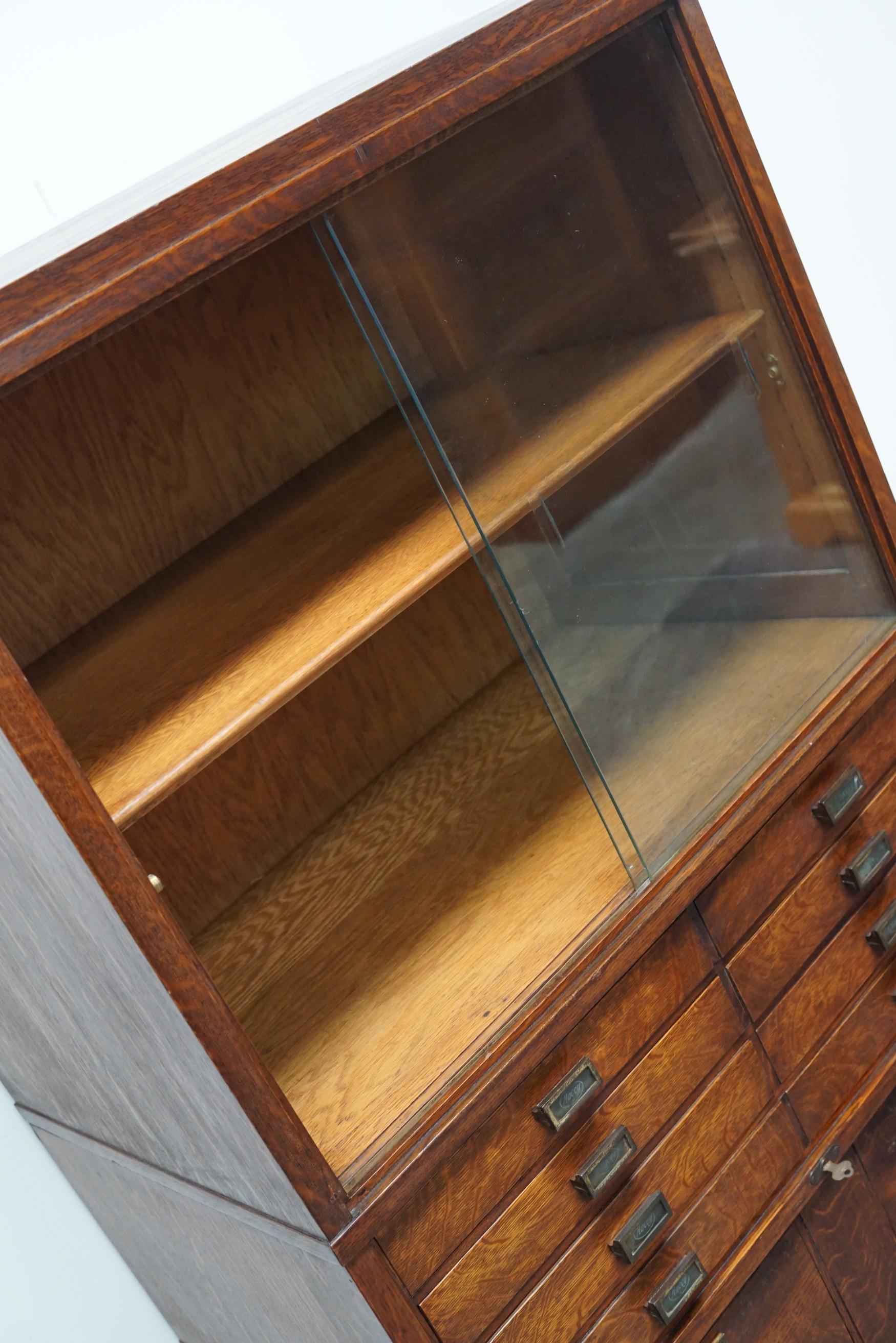 This bookcase / filing cabinet was produced by Macey in the US around 1920. It features stackable compartments with two glass sliding doors in the top section and drawers in the bottom. The interior dimensions of the drawers are: DWH 44 x 36 x 5 cm