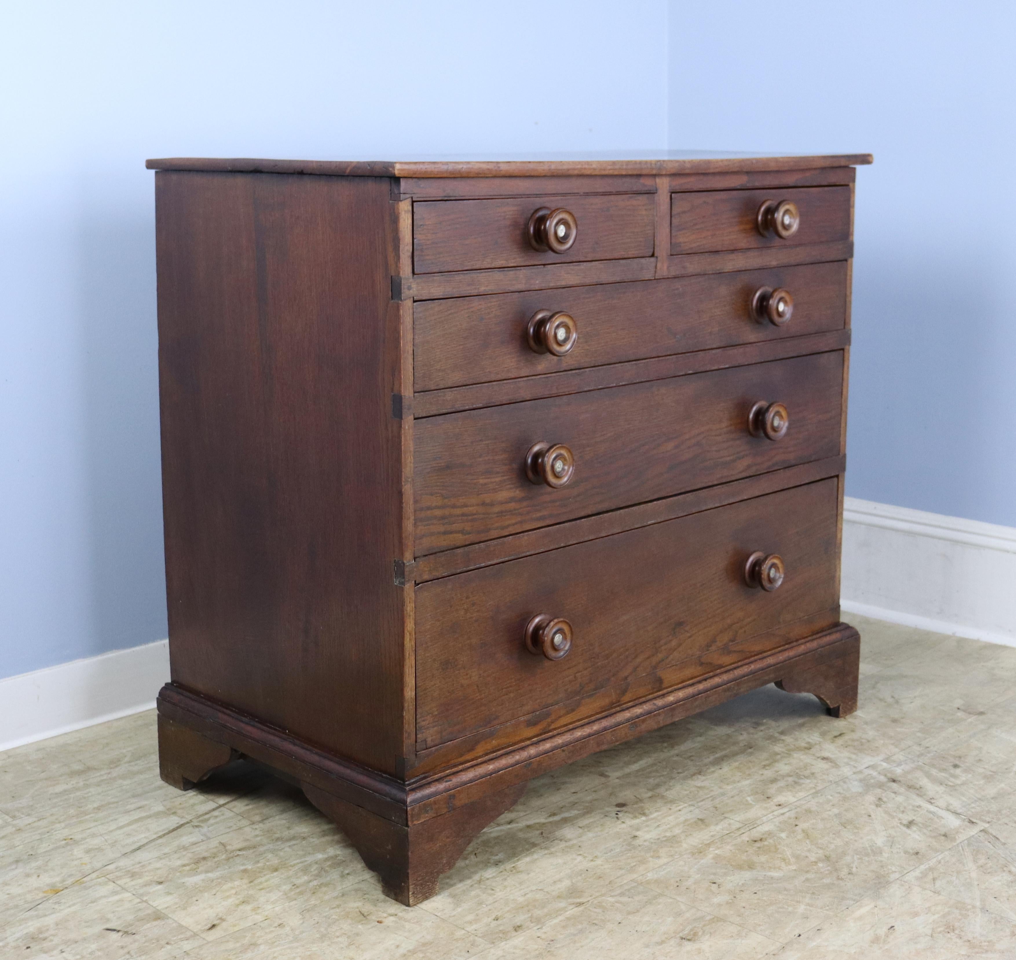 A handsome oak chest of drawers with 2 over 3 construction  Ogee feet and decorative knobs.  There is a small repair on the bottom drawer, shown in thumbnail, and some fading on the top.  Nice size for a guest or child's bedroom.