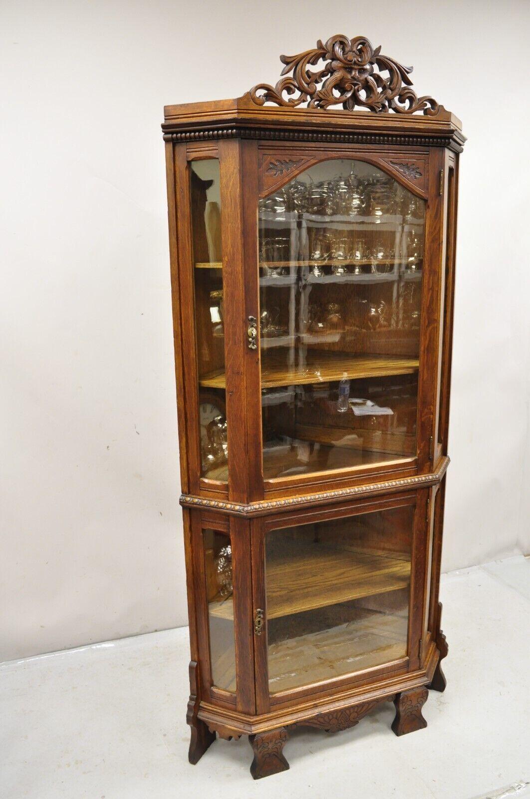 Antique Oak Victorian Renaissance Glass Door Carved Curio Corner China Cabinet. Item features carved Northwind face fretwork pediment, 2 glass swing doors, working lock and key for upper door, 3 wooden shelves, original wavy glass (except one small