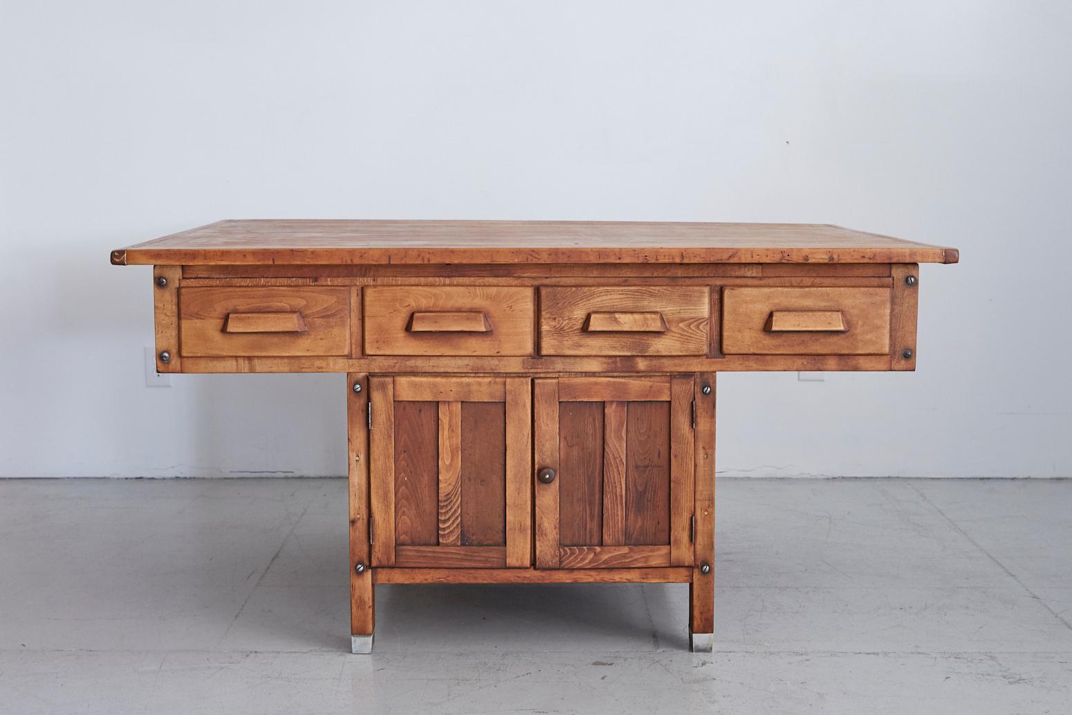 Great two-sided antique oak work table or desk. Large top surface with nice wear and patina throughout and four drawers on each side. Large base with doors enclosing open storage, also on both sides. Metal cap feet. Would make be a great communal