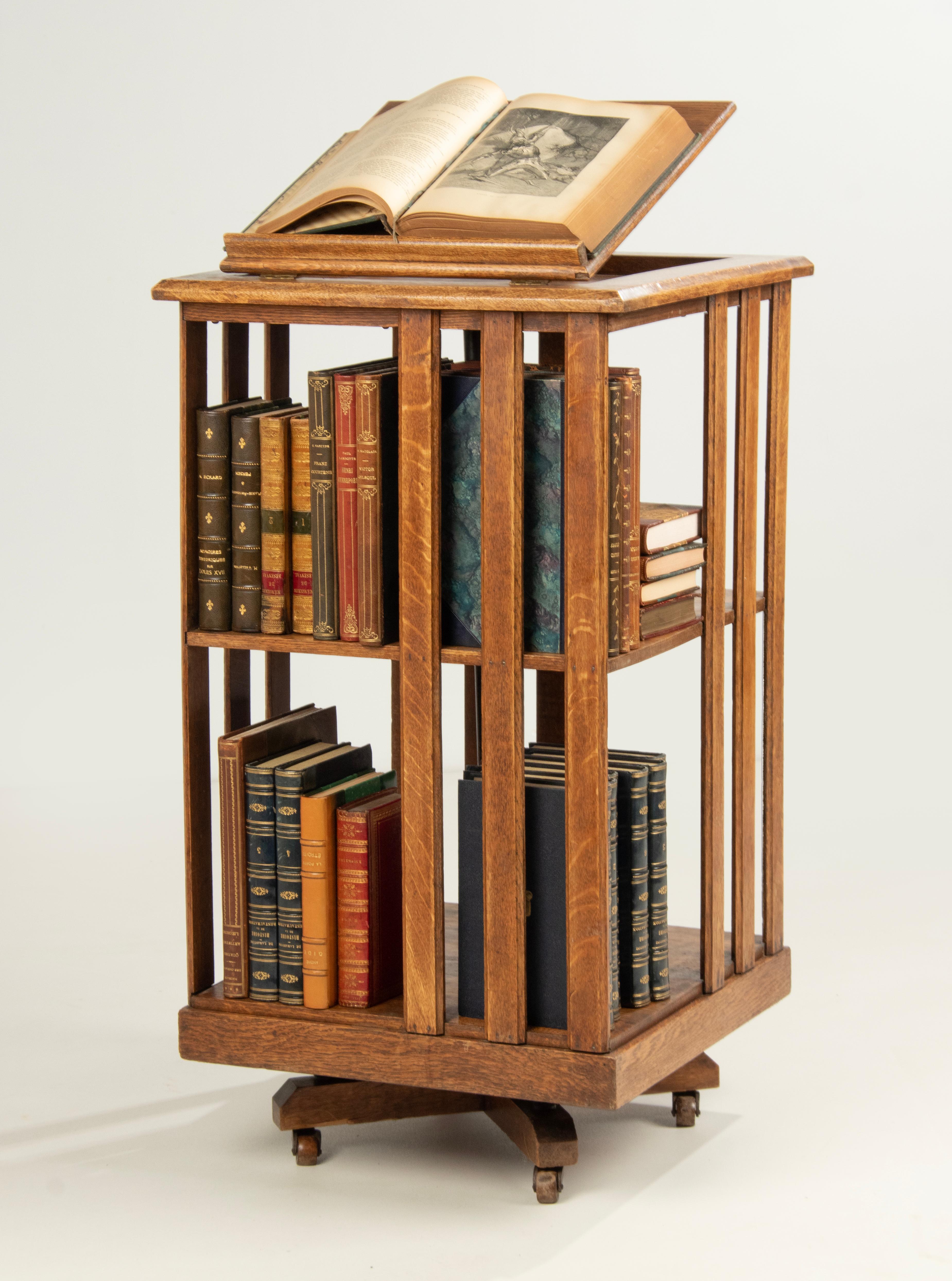 An antique solid oak revolving bookcase. Made and marked John Danner Manufacturing Co., Clayton Ohio. The bookmill can rotate by the central iron rod, resting on a cast iron base with underneath wheels. It has two tiers covered with slat sides,