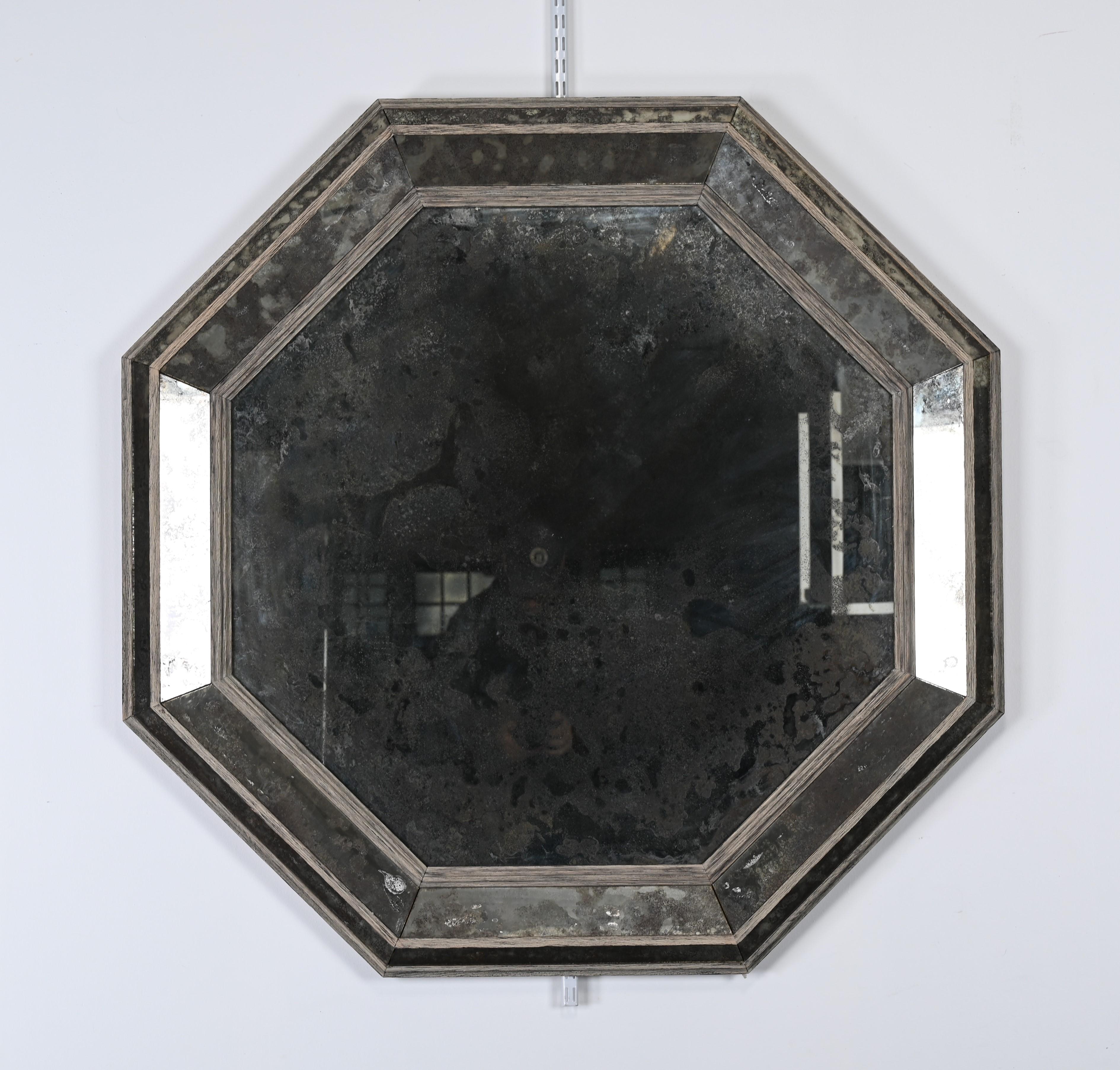 An understated Hollywood Regency-style antiqued mirror in distressed painted grey oak by Niermann Weeks. This designer mirror has great scale and importance. Would look great in a modern or decorative interior. This mirror is structurally sound and