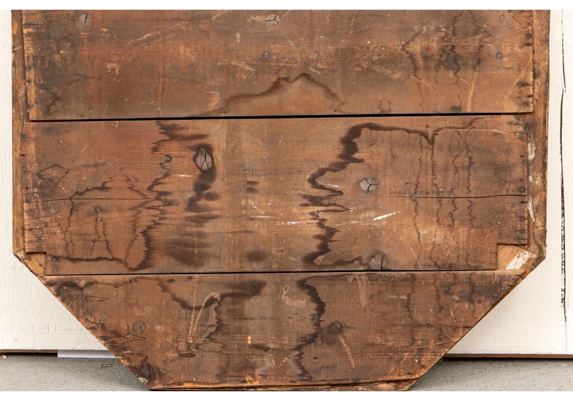 Un octogonal  Miroir en bois façonné et en métal moulé avec une crête façonnée avec un masque d'ange ailé en fonte Primitive appliqué. Les bandes extérieures et intérieures en miroir de l'entourage sont ornées de palmettes argentées et de masques