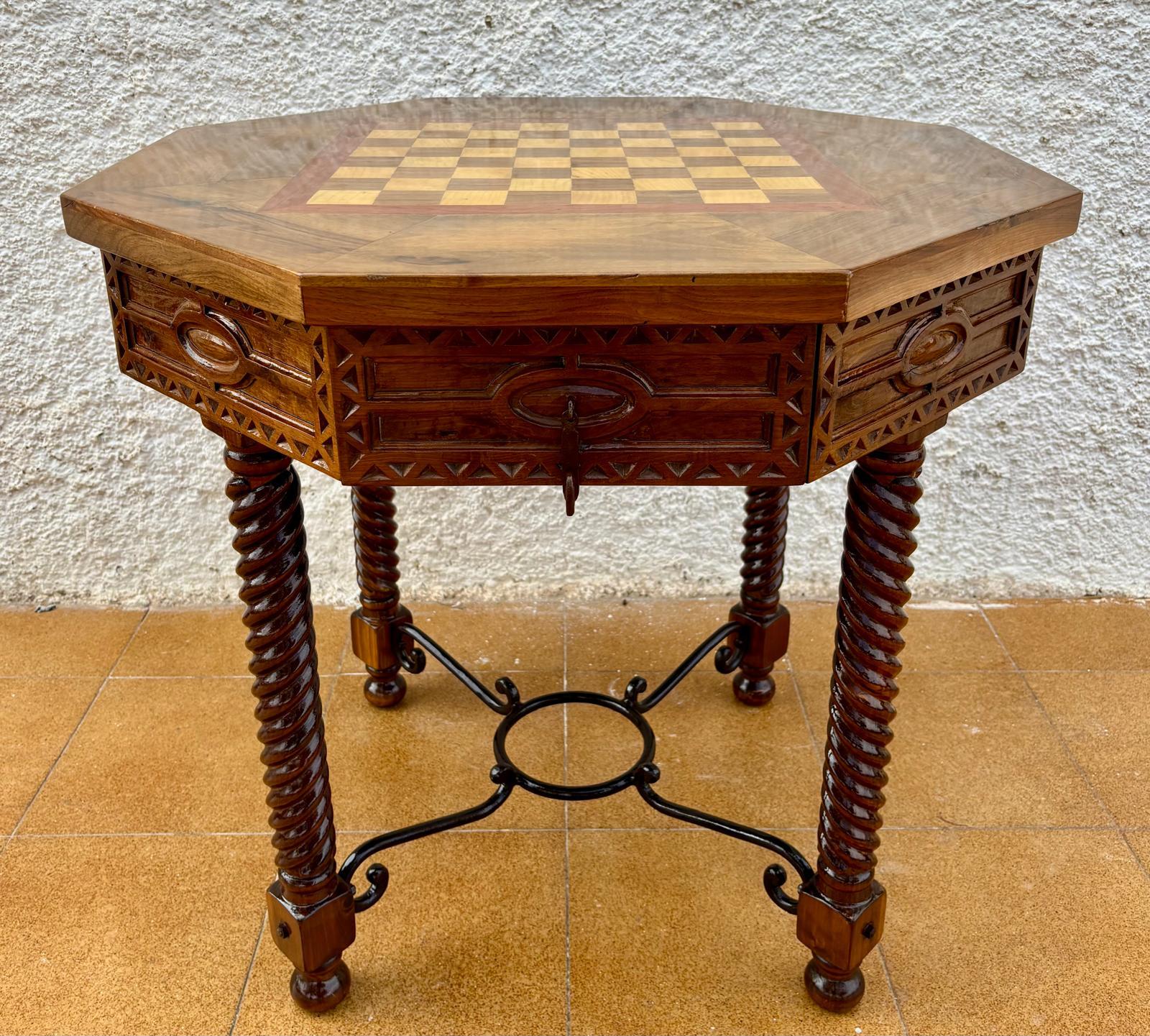 Antique octagonal table on twisted legs.
Made in France at the beginning of the 20th century.
It is made of solid oak wood, with its checkerboard top and two beautifully carved drawers, with hard iron handles.
Its four turned legs are joined by a