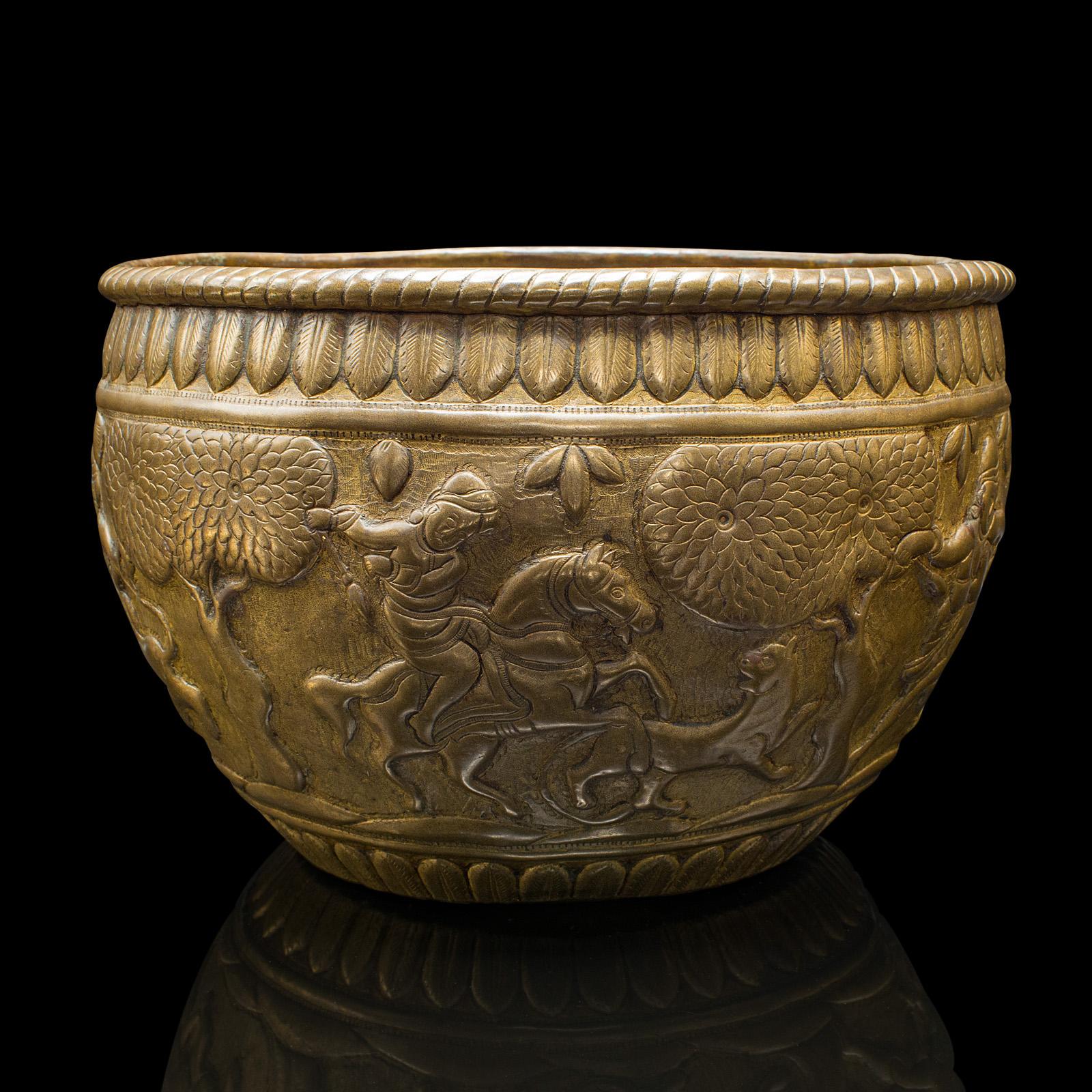 
Il s'agit d'un ancien bol à offrandes servant de jardinière. Pot de jardinage en relief en laiton d'Asie du Sud-Est, datant de la fin de la période victorienne, vers 1900.

Fascinante finition repoussée avec des scènes distinctives sur la forme du