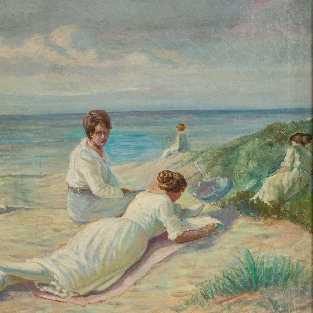 A bright seascape with a group of women dressed in white, lounging in the sun on a beach of sand dunes with a sailboat in the distance. The idyllic summer seaside day creates feelings of ease and contentment. The painting is mounted in a giltwood