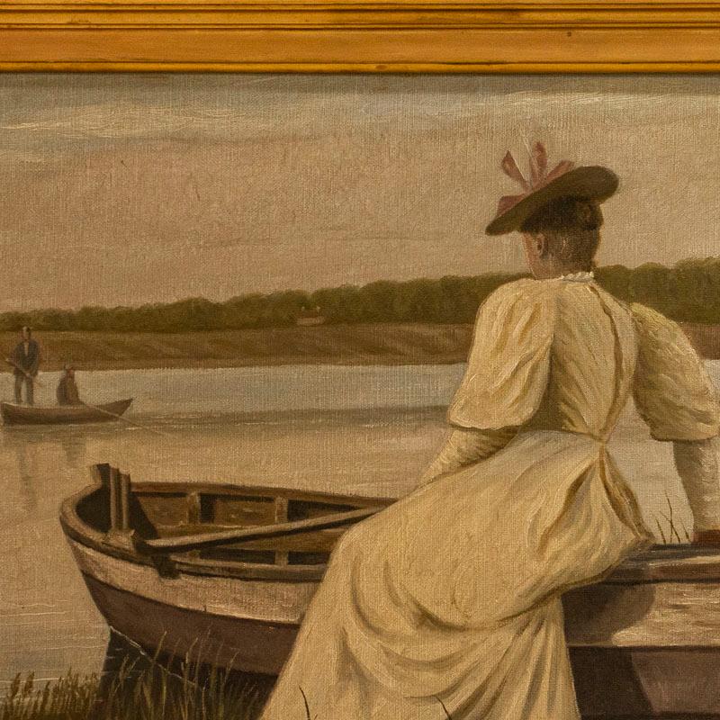 This peaceful painting portrays a young woman in long white summer dress, sitting on the edge of a boat in the shallows of a lake. She is watching two men fish off of another boat in the distance. Her mutton sleeve dress, hat with pink ribbon and