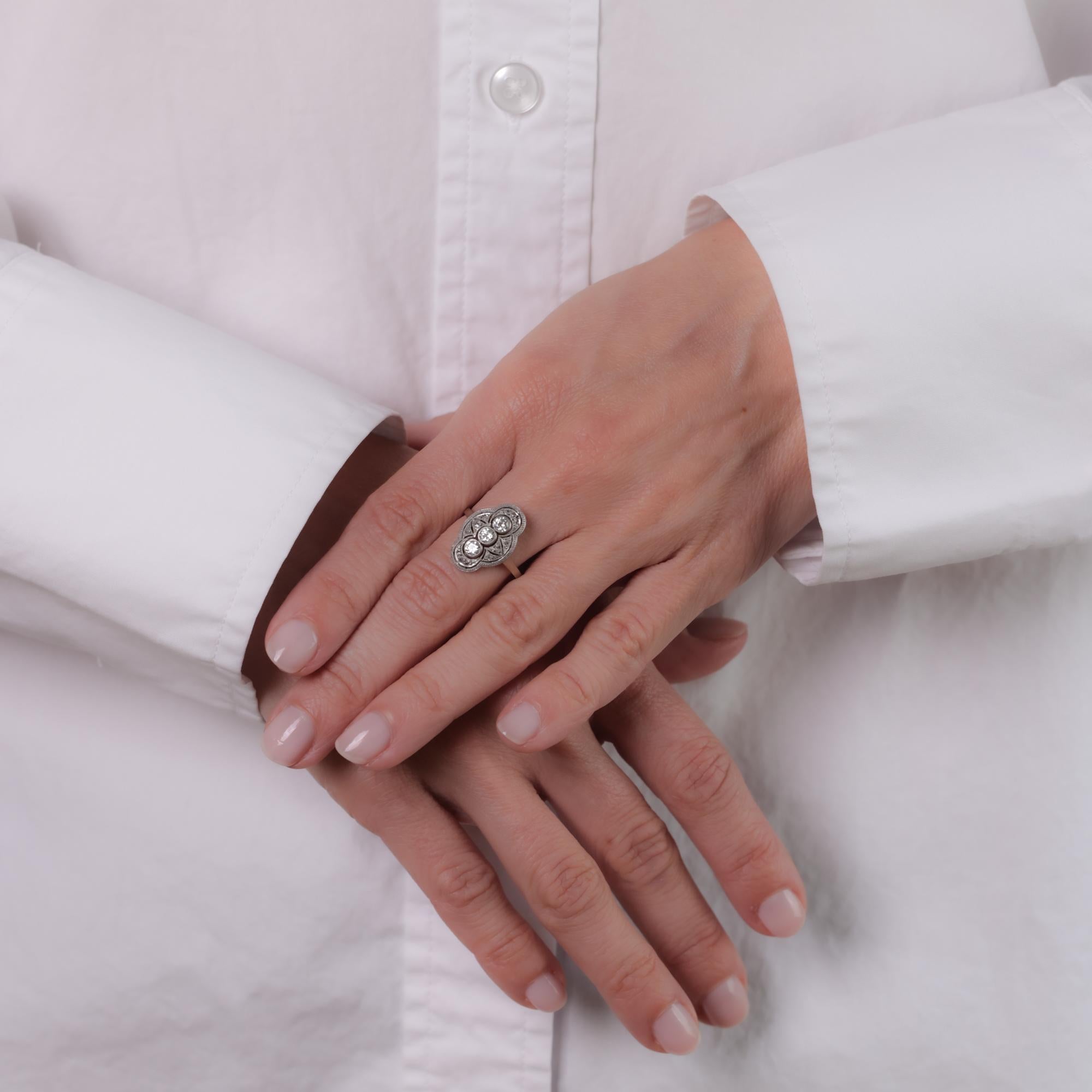 Este anillo antiguo de oro blanco de 14k presenta tres diamantes talla europea antigua que suman aproximadamente 0,50 quilates, acentuados por 12 diamantes talla rosa que suman aproximadamente 0,10 quilates, todos de color H y claridad SI. Alrededor