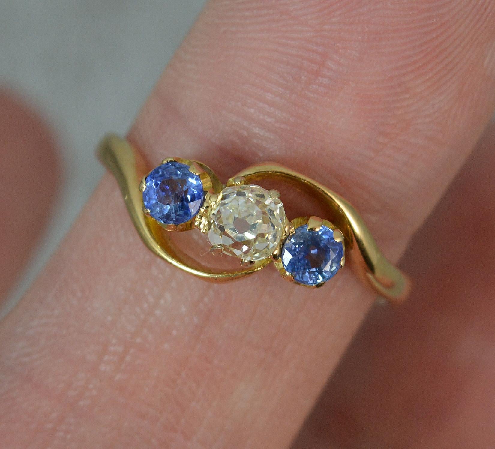 A superb Sapphire and Diamond trilogy ring on twist. c1890.
Solid 18 carat yellow gold example.
Designed with a 0.35-0.4 carat deep old cut natural diamond to the centre with a Ceylon origin sapphire to each side.
12mm spread of stones.

CONDITION ;