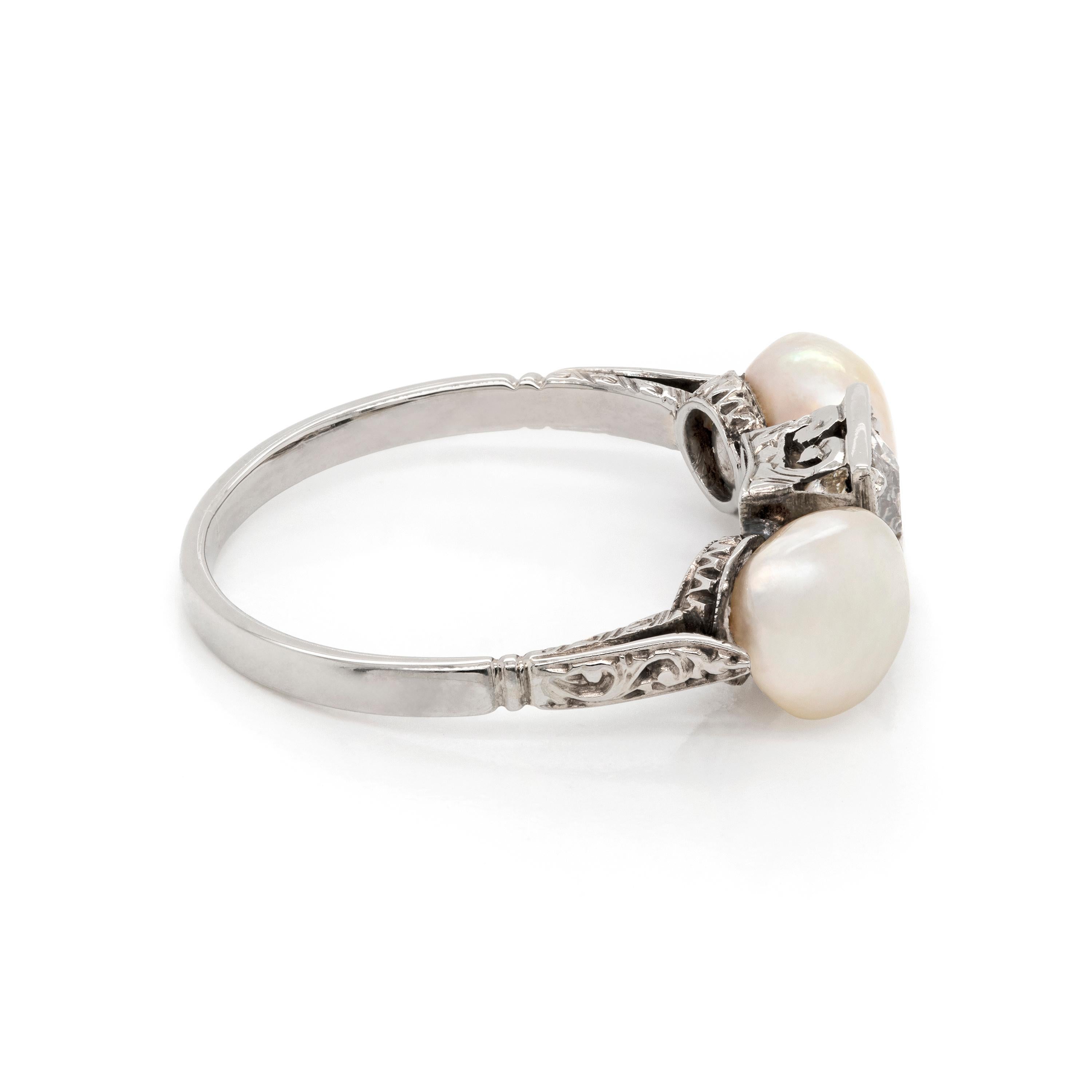 One of a kind Art Deco 18 carat white gold ring featuring two 6.9mm button natural pearls mounted on either side of a beautifully carved square frame measuring 0.65 x 0.65cm, atop a fine leaf detailed shank. A claw set old European cut diamond,