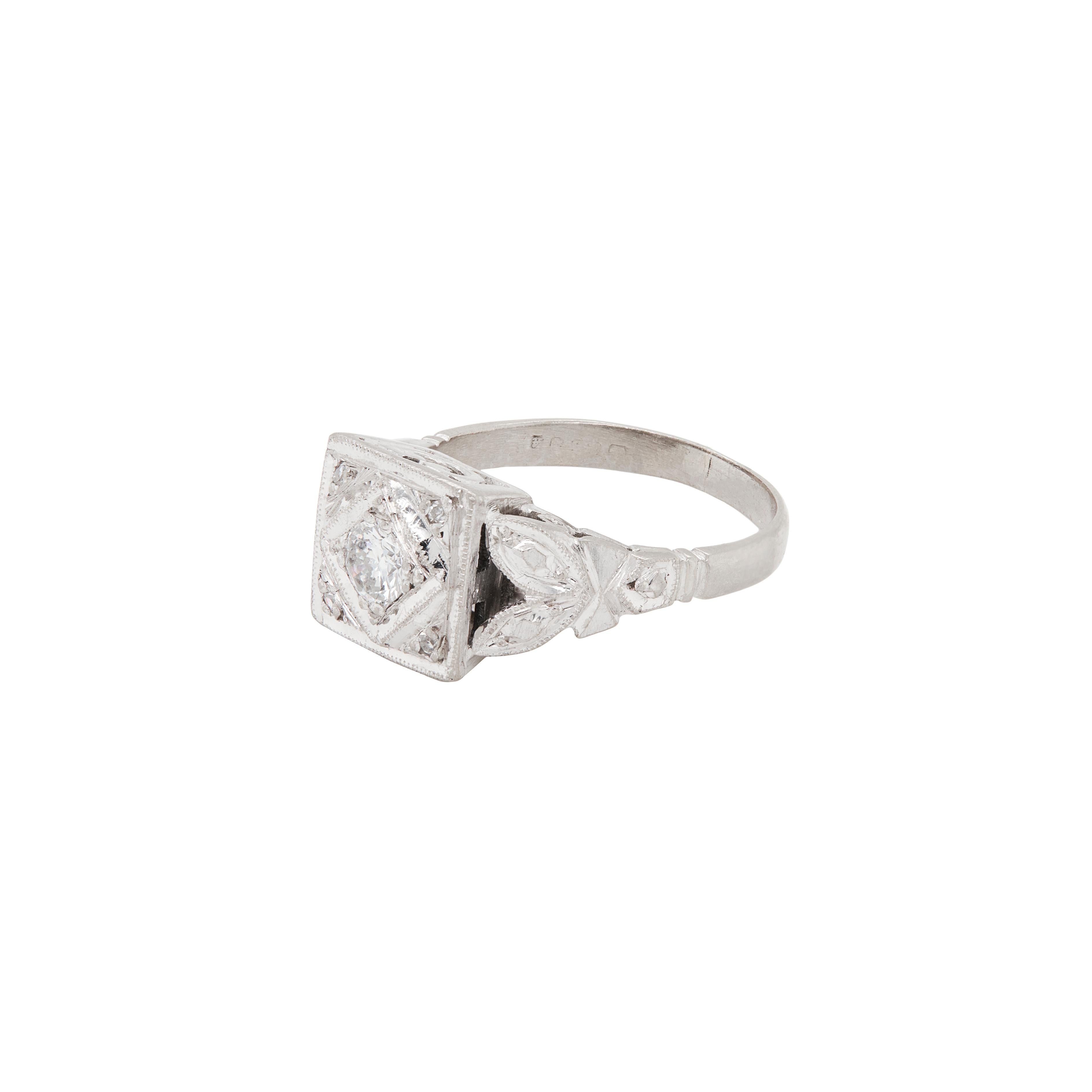 Hand crafted with fantastic attention to detail, this wonderful Art Deco dress ring is a celebration of the 20th Century. 

The ring features a striking central round brilliant cut diamond nestled within a beautifully sculpted square shaped 1 x 1 cm
