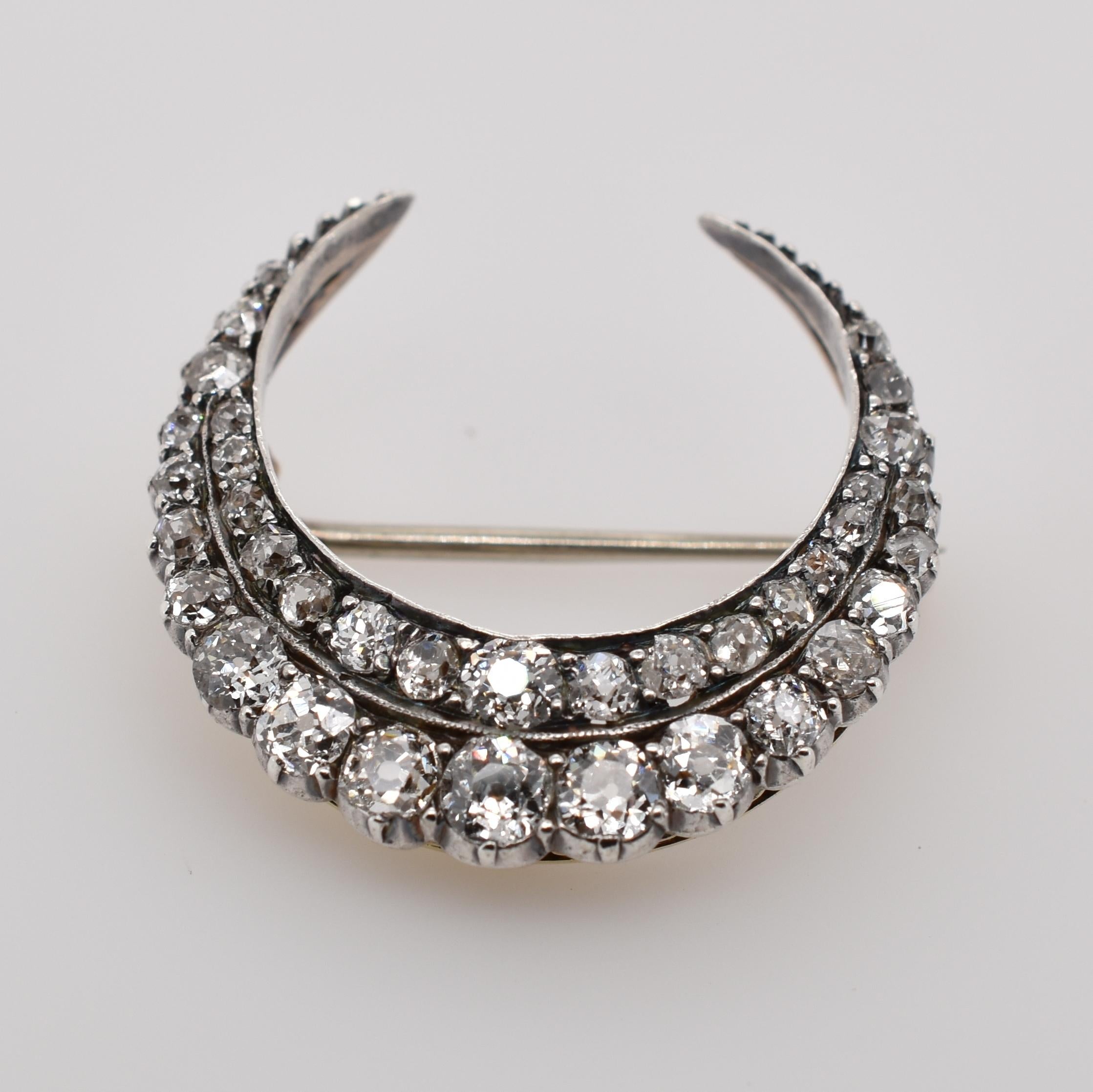 18ct white gold and sterling silver antique old cut diamond crecent shaped brooch. 36 old cut diamonds totalling 1.40ct. 