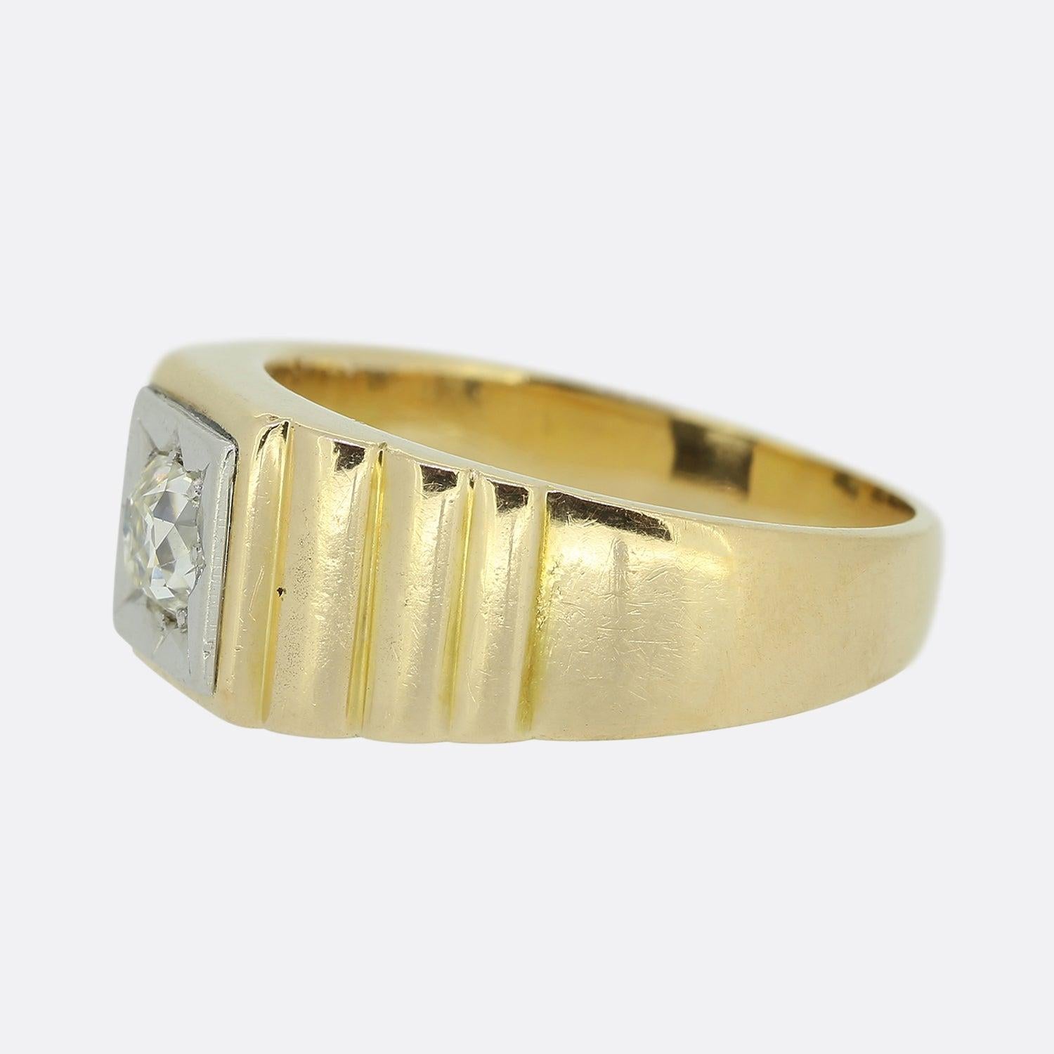 Here we have an antique 18ct yellow gold diamond signet ring. The ring features a single round faceted old cut diamond at the centre of the face in a platinum star-burst setting. The piece is finished with wide stepped shoulders and an otherwise