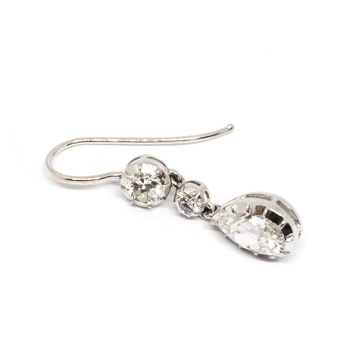 Diamond drop earrings in cut down style settings, with two round brilliant-cut diamonds and old-cut diamond drop shape diamond at the bottom. Each pear shape diamond weighing approximatley 1.00cts. Estimated total diamond weight 2.36cts