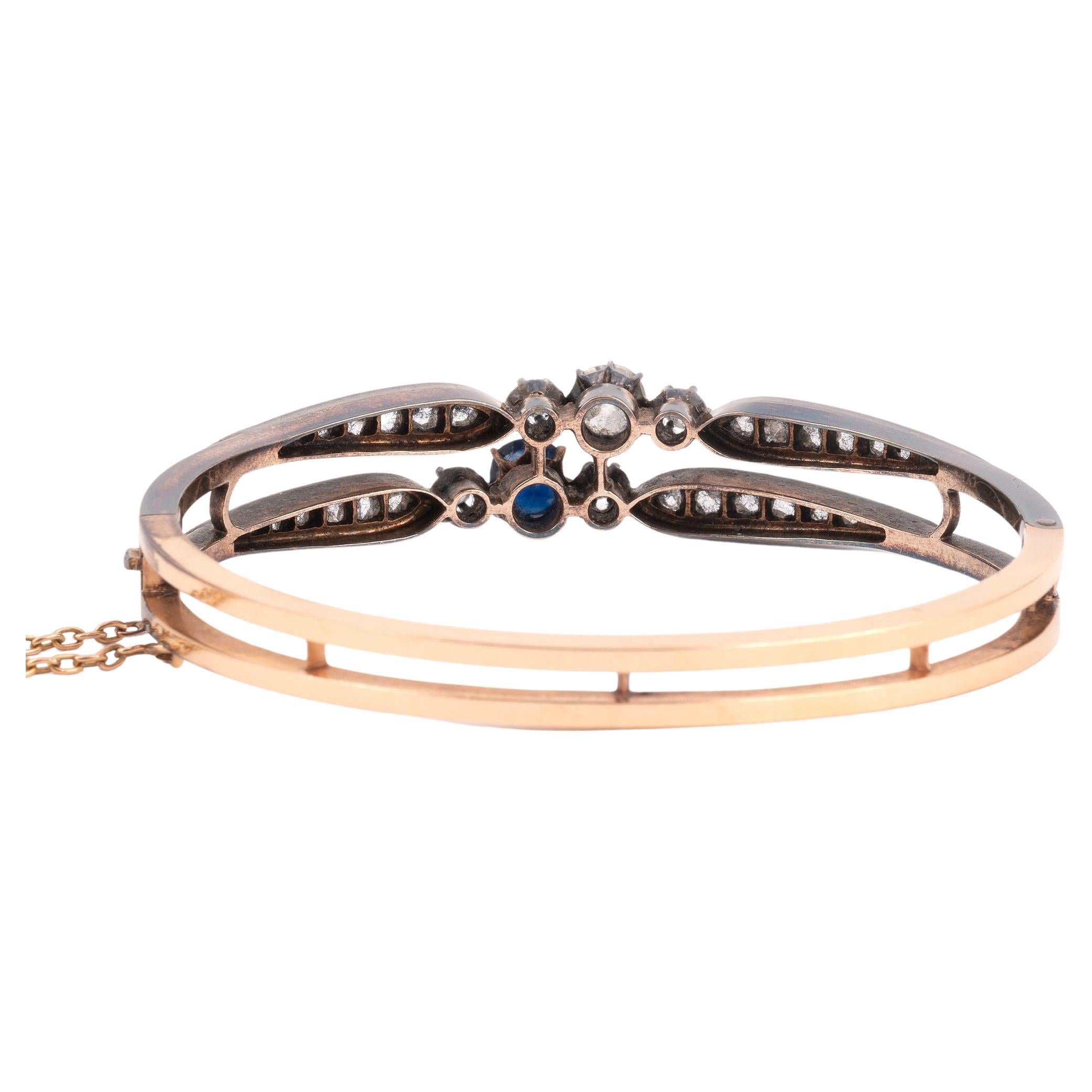 Bracelet ouvrant en or 18K et argent, serti d'un saphir et d'un diamant rond de taille ancienne, entre deux lignes de diamants roses en chute. 
Œuvre italienne de la seconde moitié du XIXe siècle. 
Longueur : environ 17 cm. Poids brut : 20,1 g 

