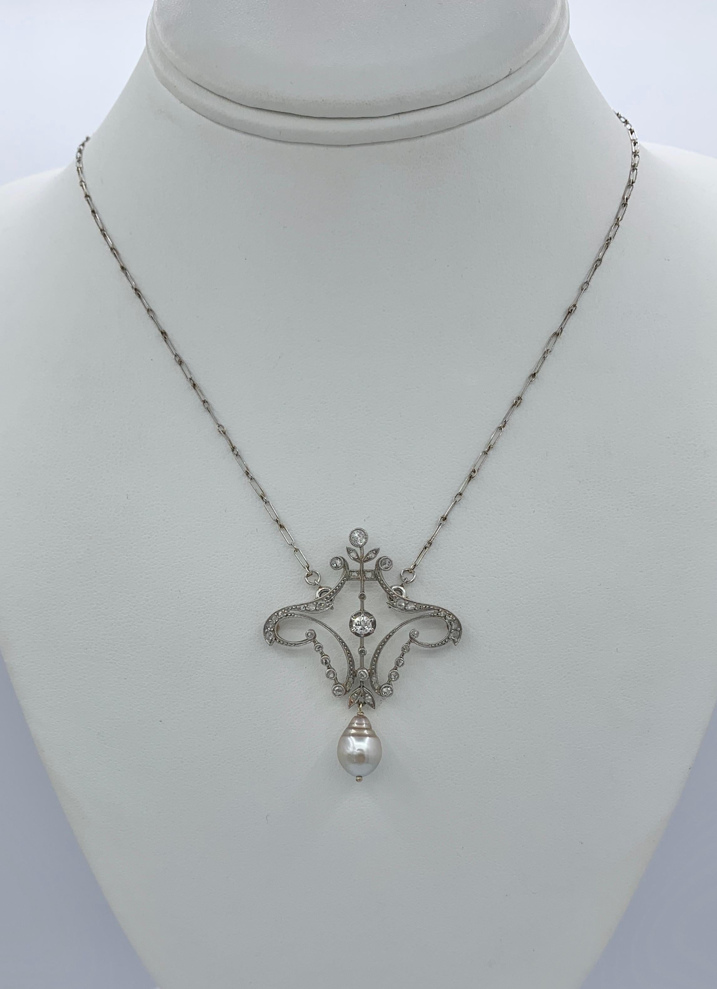 This is a spectacular Antique Victorian - Edwardian Garland Motif Pendant Necklace set with Old European and Rose Cut Diamonds in an extraordinary open work scroll motif setting in Platinum with a Pearl drop and Platinum paper clip chain.
The