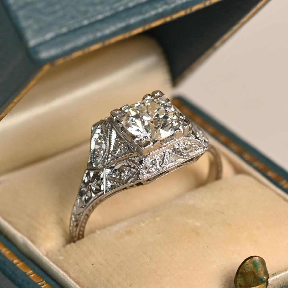 Cette exquise bague de fiançailles Art déco présente en son centre un superbe diamant de taille européenne ancienne serti clos, pesant environ 1,00 carat. De couleur J et de pureté VS1, le diamant rayonne d'une élégance et d'une brillance